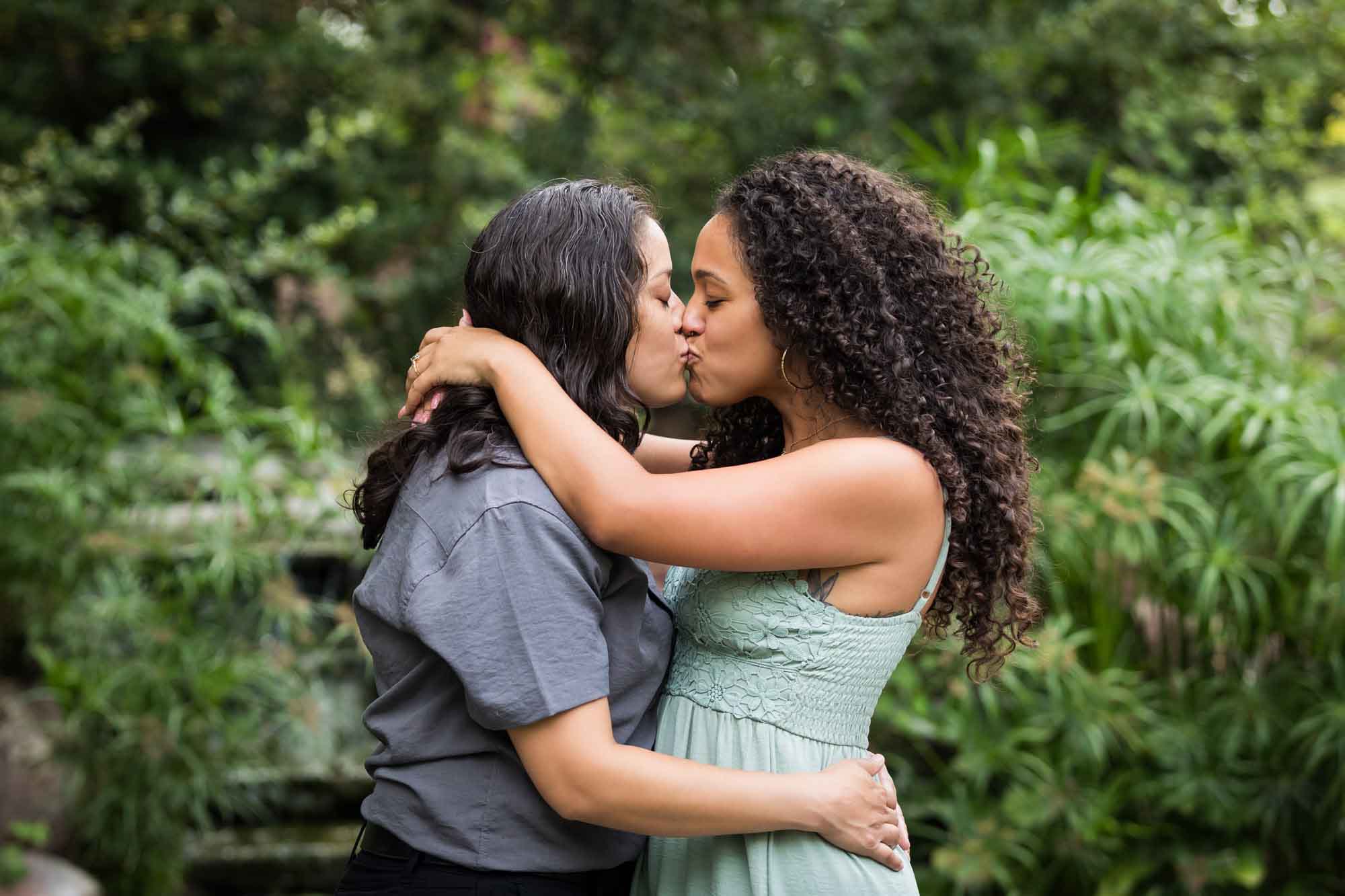 Two women kissing with green bushes and trees in background for an article about McNay Art Museum proposal tips