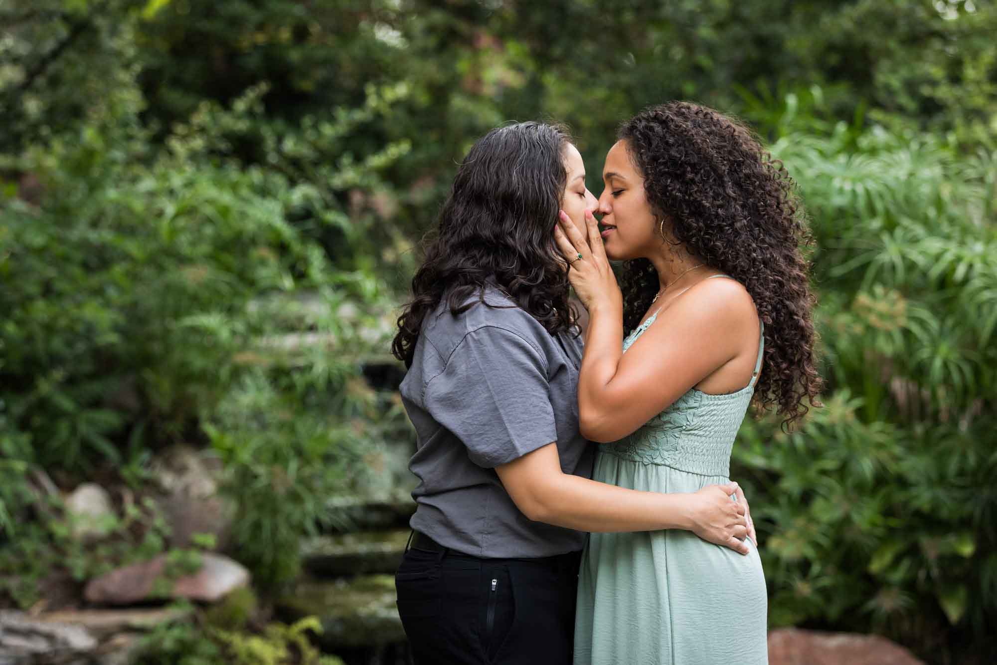 Two women kissing with green bushes and trees in background for an article about McNay Art Museum proposal tips