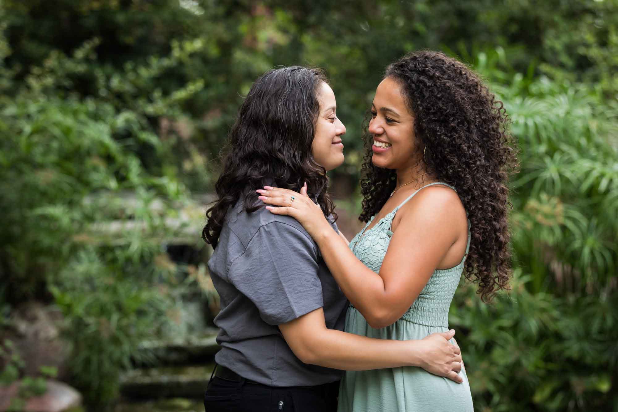 Two women hugging with green bushes and trees in background for an article about McNay Art Museum proposal tips