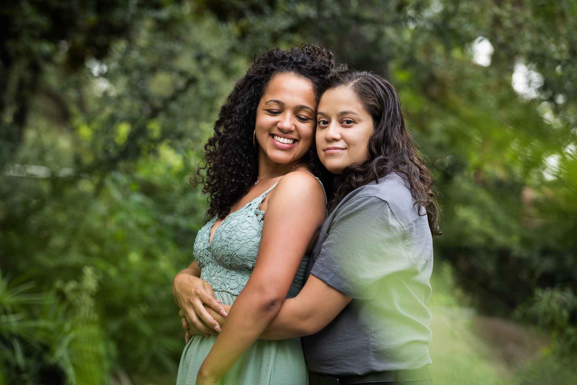 Two women hugging with green bushes and trees in background for an article about McNay Art Museum proposal tips