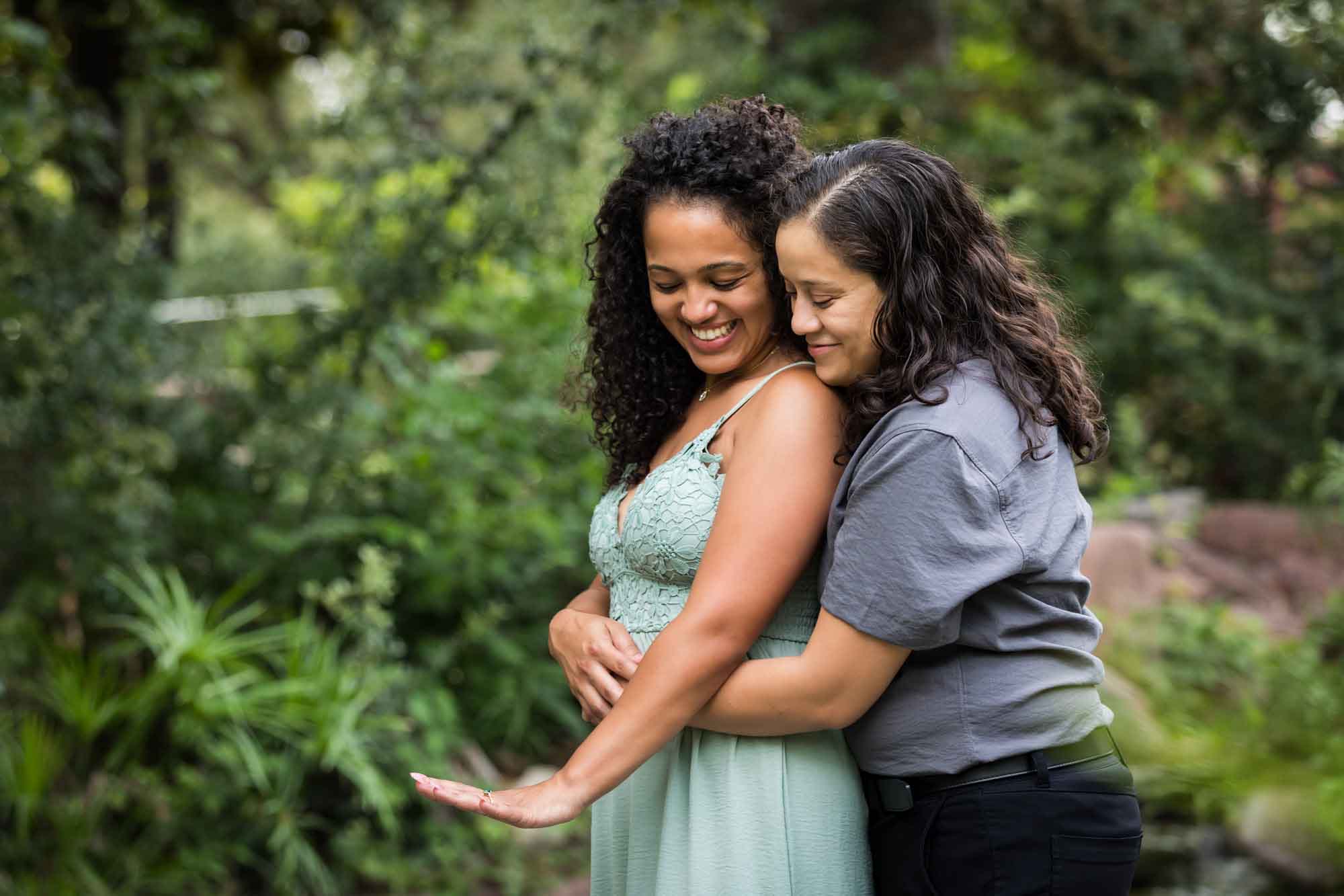 Two women hugging looking down at engagement ring on other woman's hand for an article about McNay Art Museum proposal tips