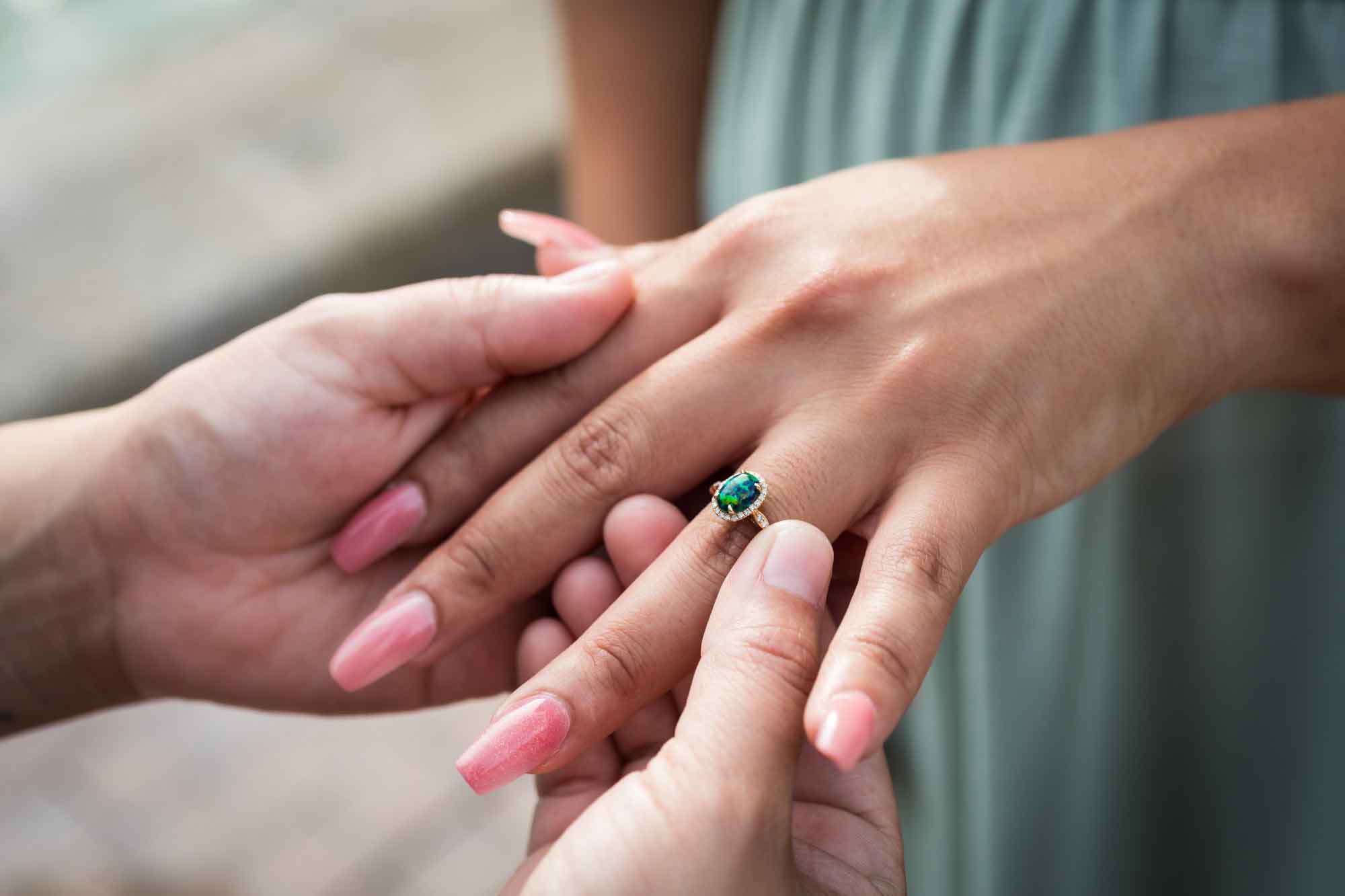Woman putting engagement ring on another woman's hand 