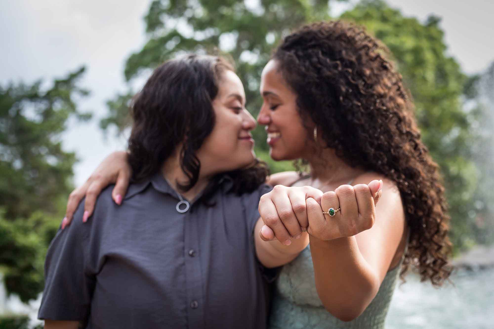 Two women looking at each other with hands extended showing engagement ring