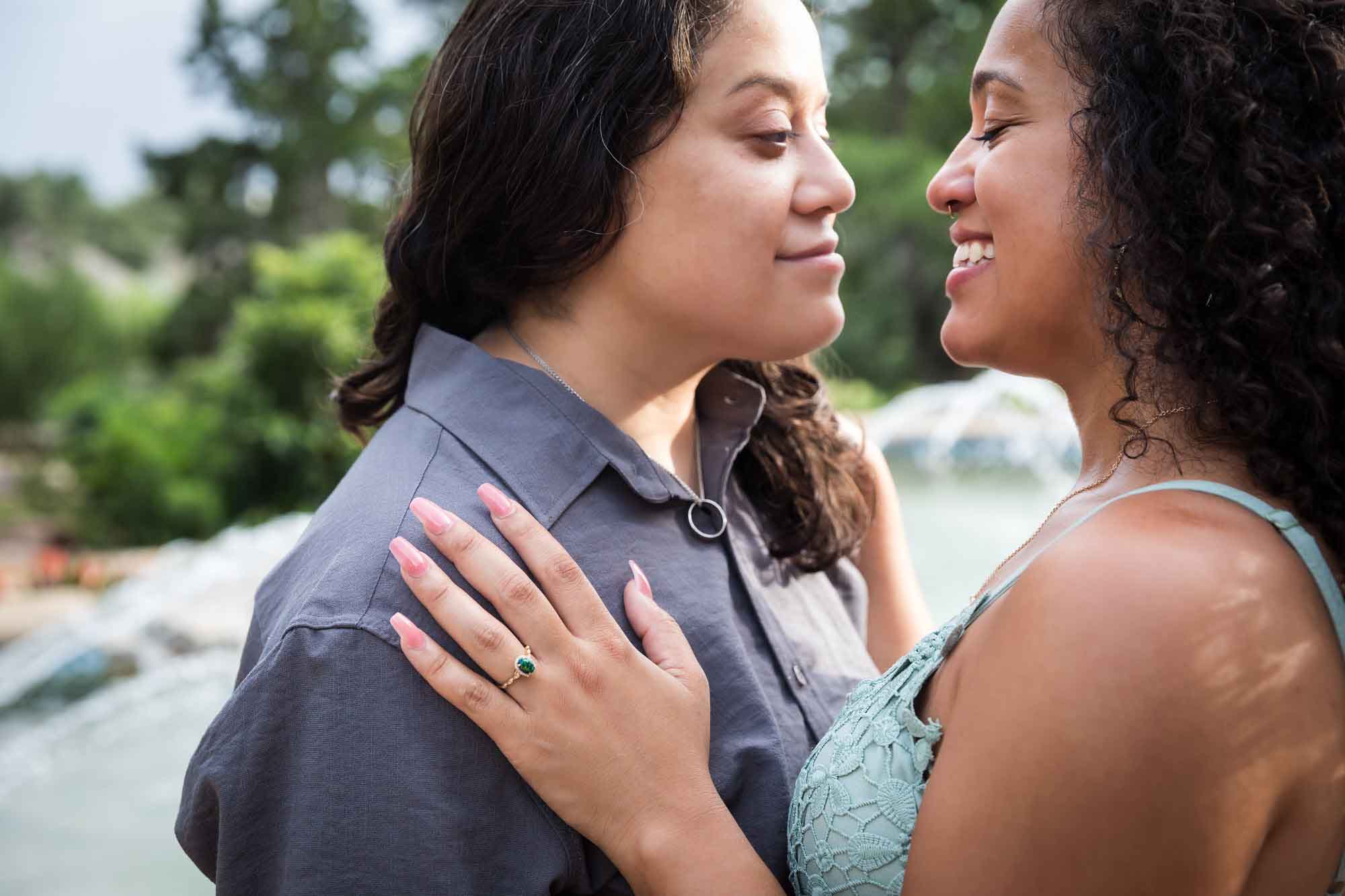 Two women hugging with one woman's hand on another showing engagement ring