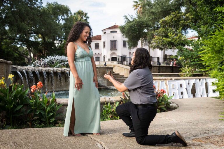 Woman proposing to another woman in front of fountain for an article about McNay Art Museum proposal tips