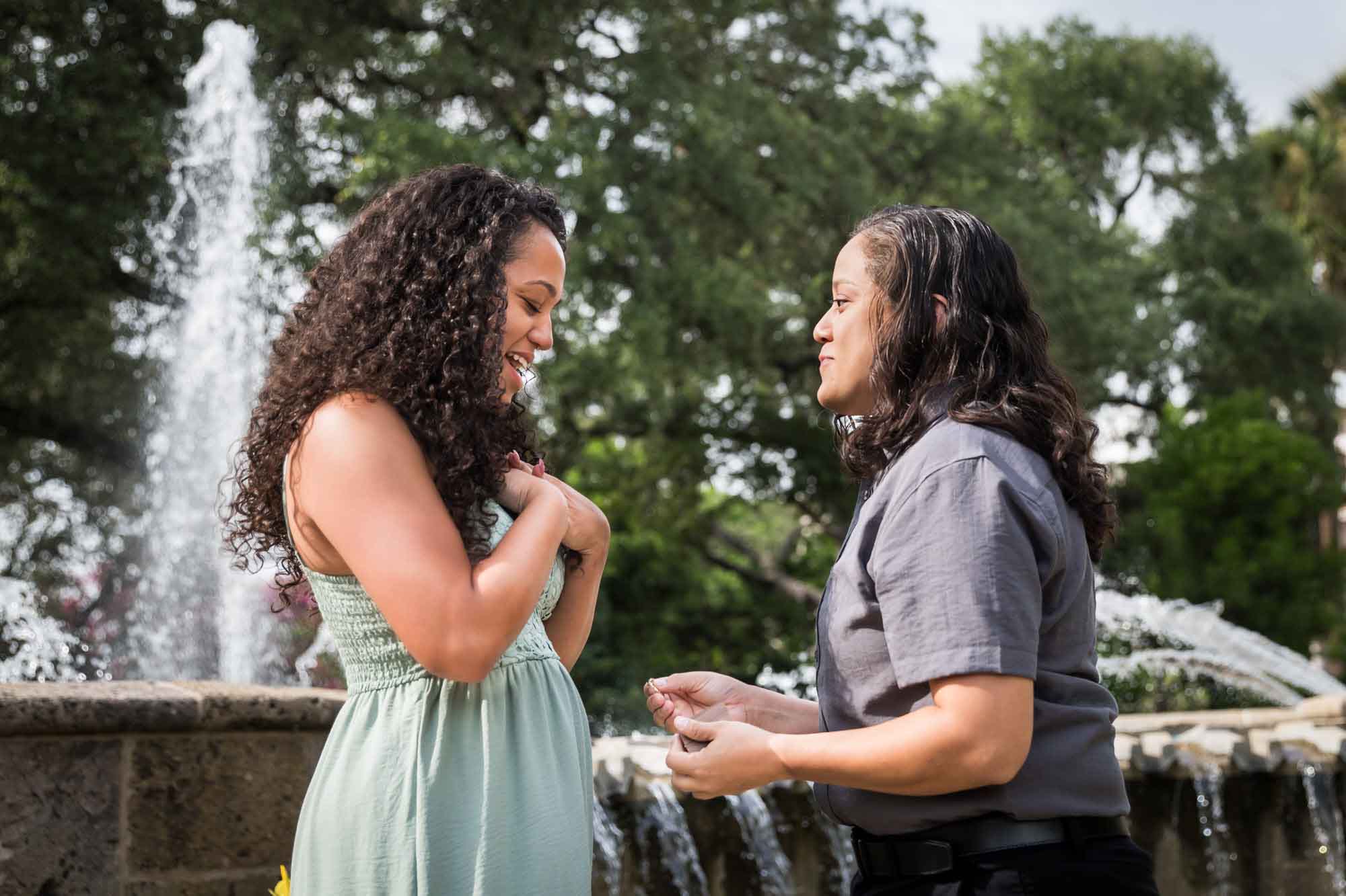 Woman proposing to another woman in front of fountain for an article about McNay Art Museum proposal tips
