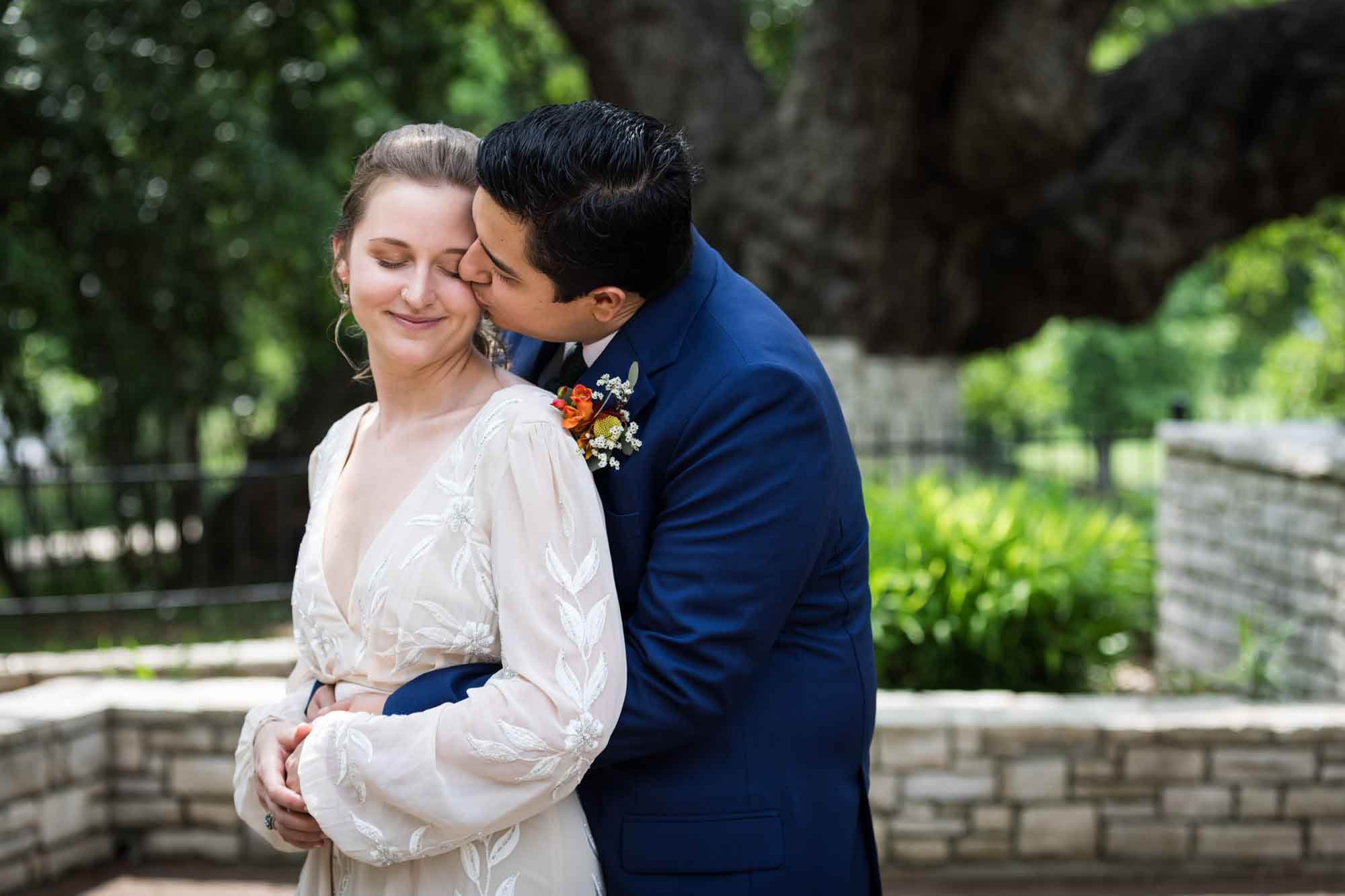 Groom kissing bride on the cheek in Landa Park for an article on affordable wedding venues in San Antonio