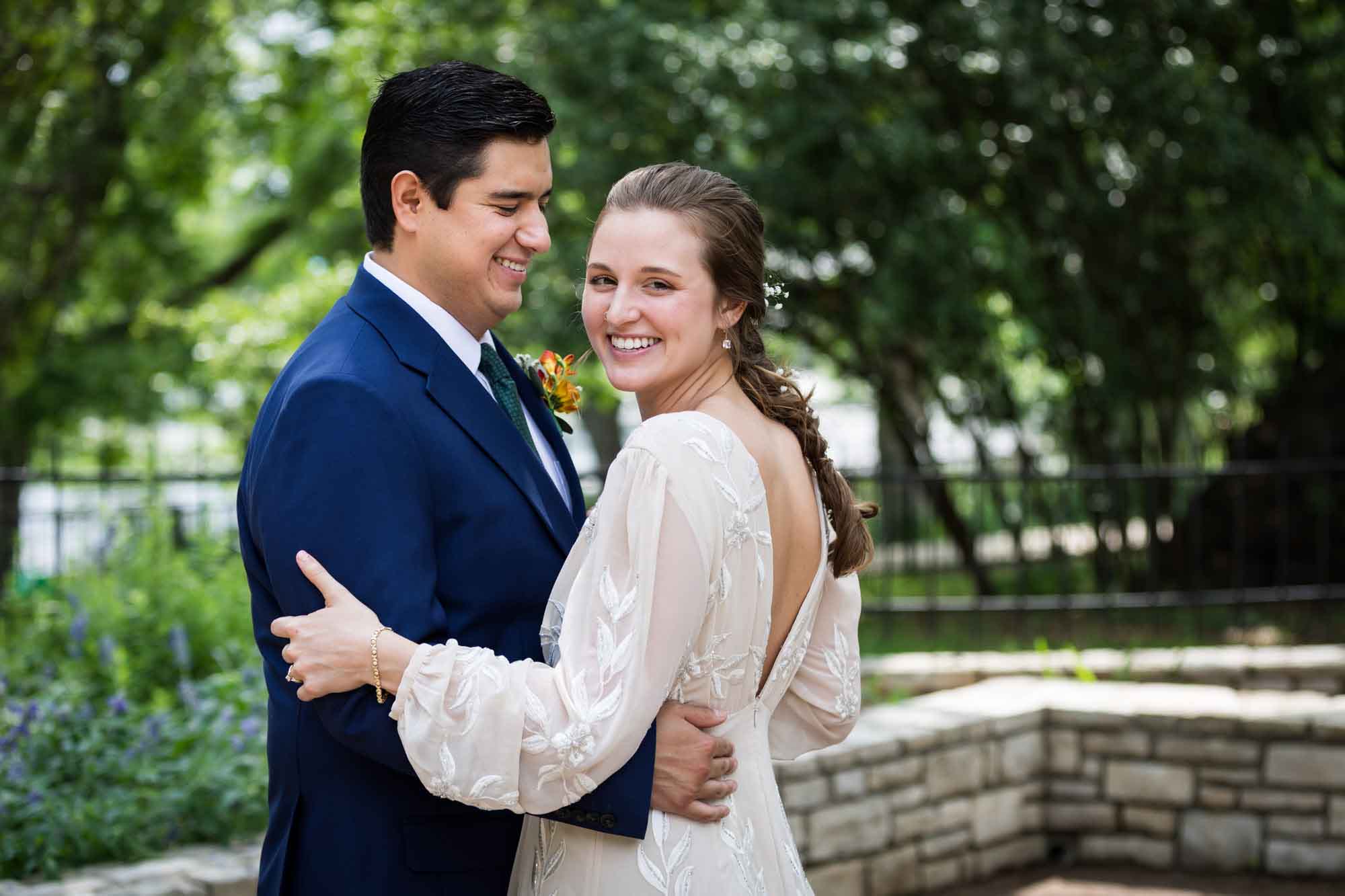 Bride and groom hugging in front of trees in Landa Park for an article on affordable wedding venues in San Antonio