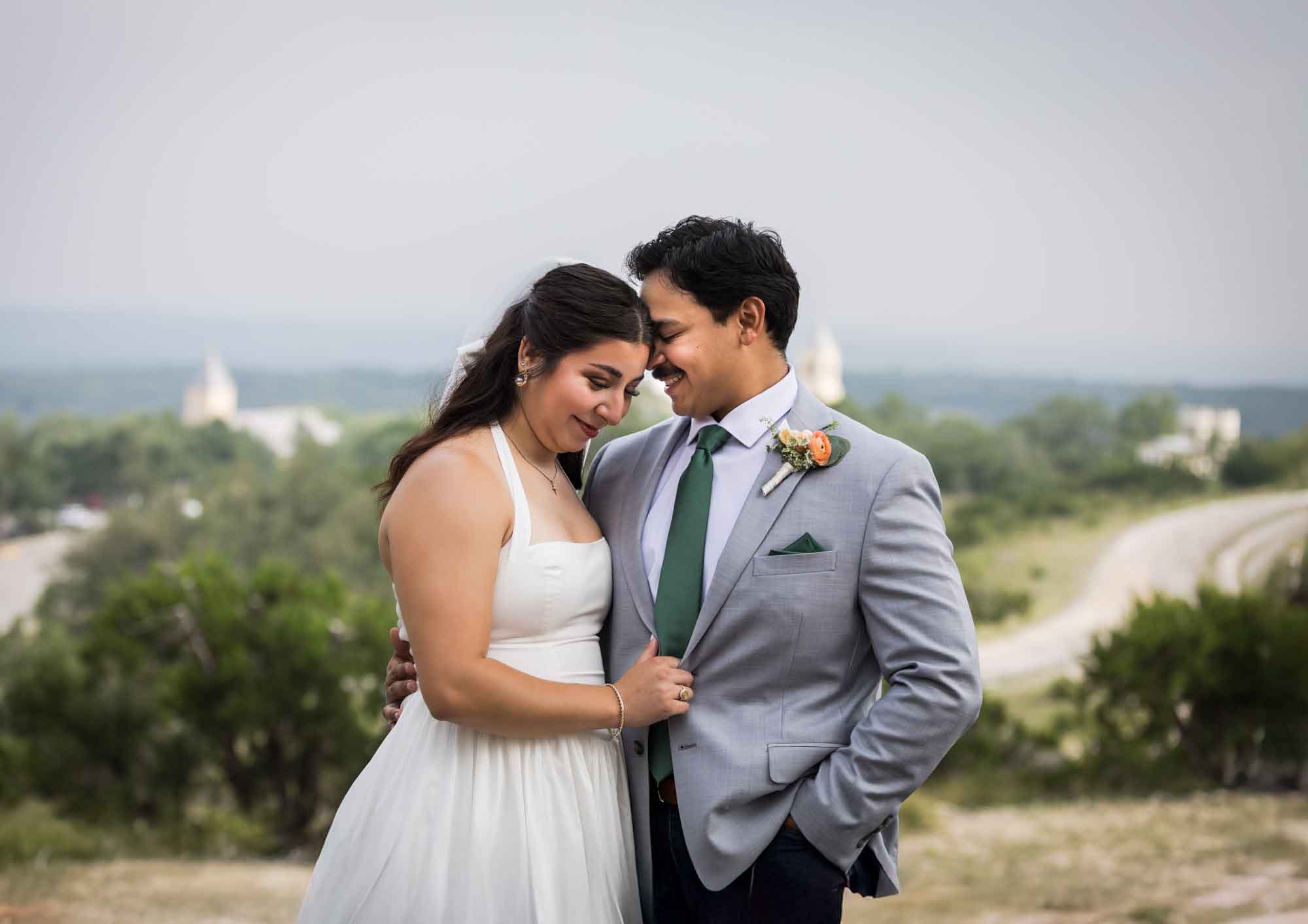 Bride and groom hugging with hill country view in the background for an article on affordable wedding venues in San Antonio