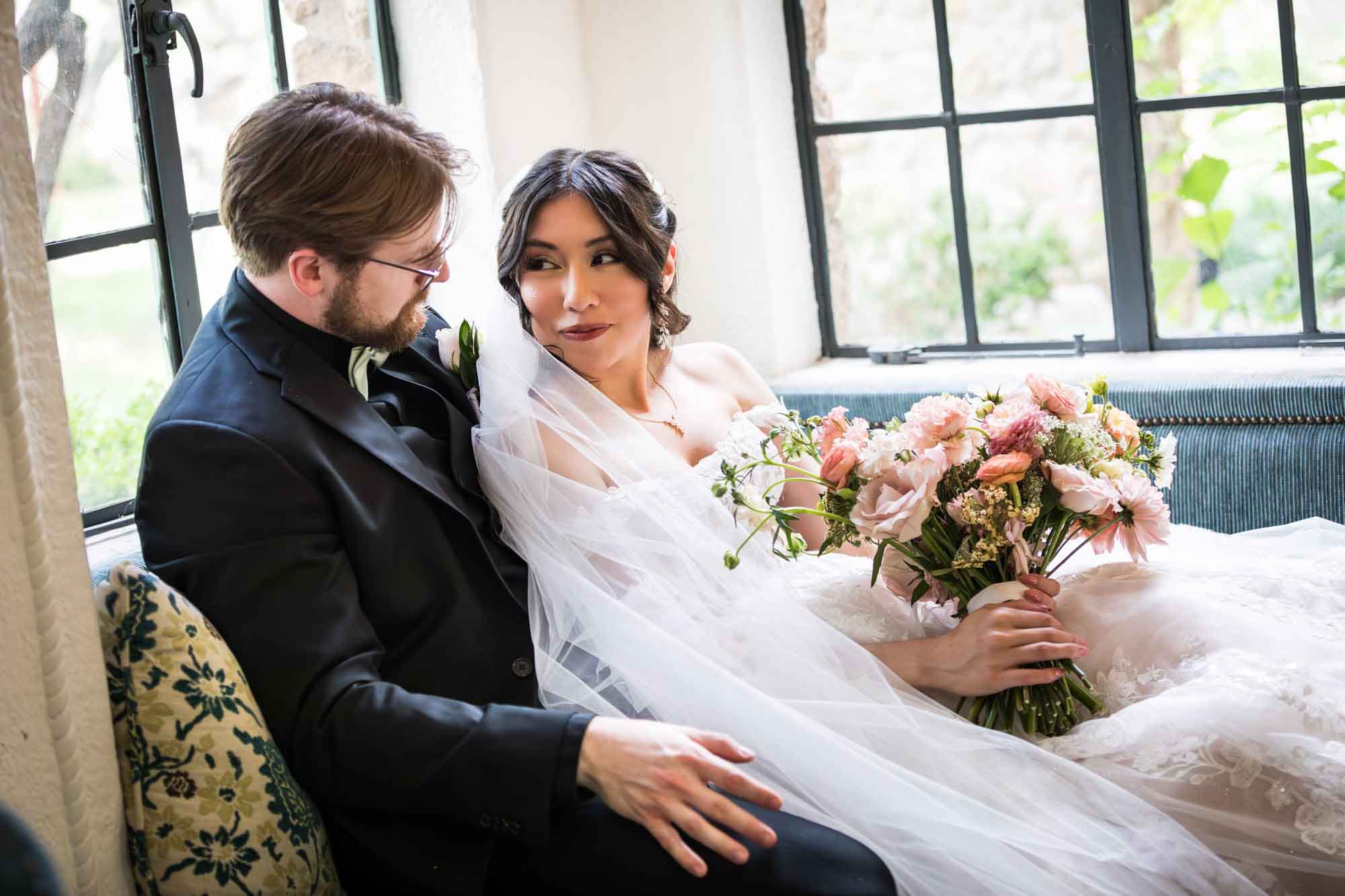 Bride and groom looking at each other seated in front of windows at The Veranda for an article on affordable wedding venues in San Antonio