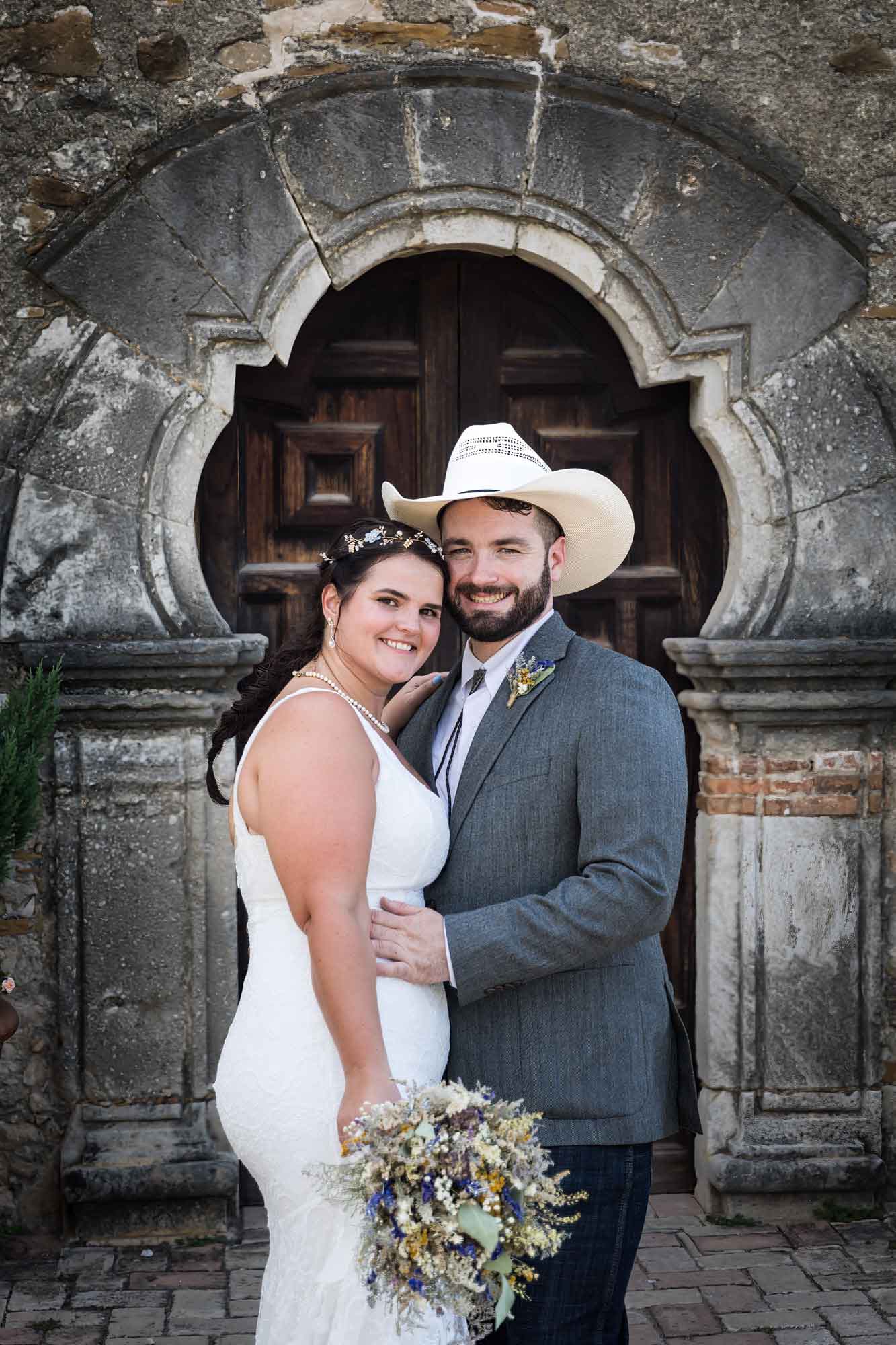 Bride and groom hugging in entrance to Mission Espada for an article on affordable wedding venues in San Antonio