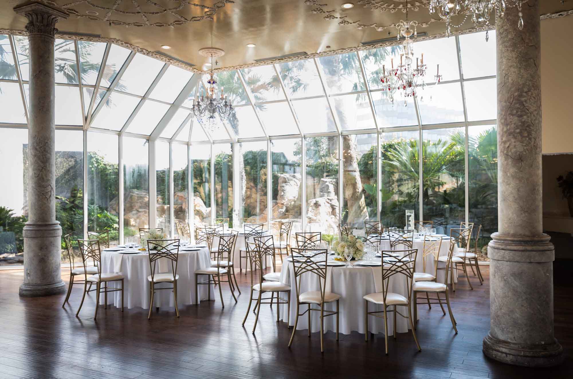Room with glass walls and round tables for an article on affordable wedding venues in San Antonio