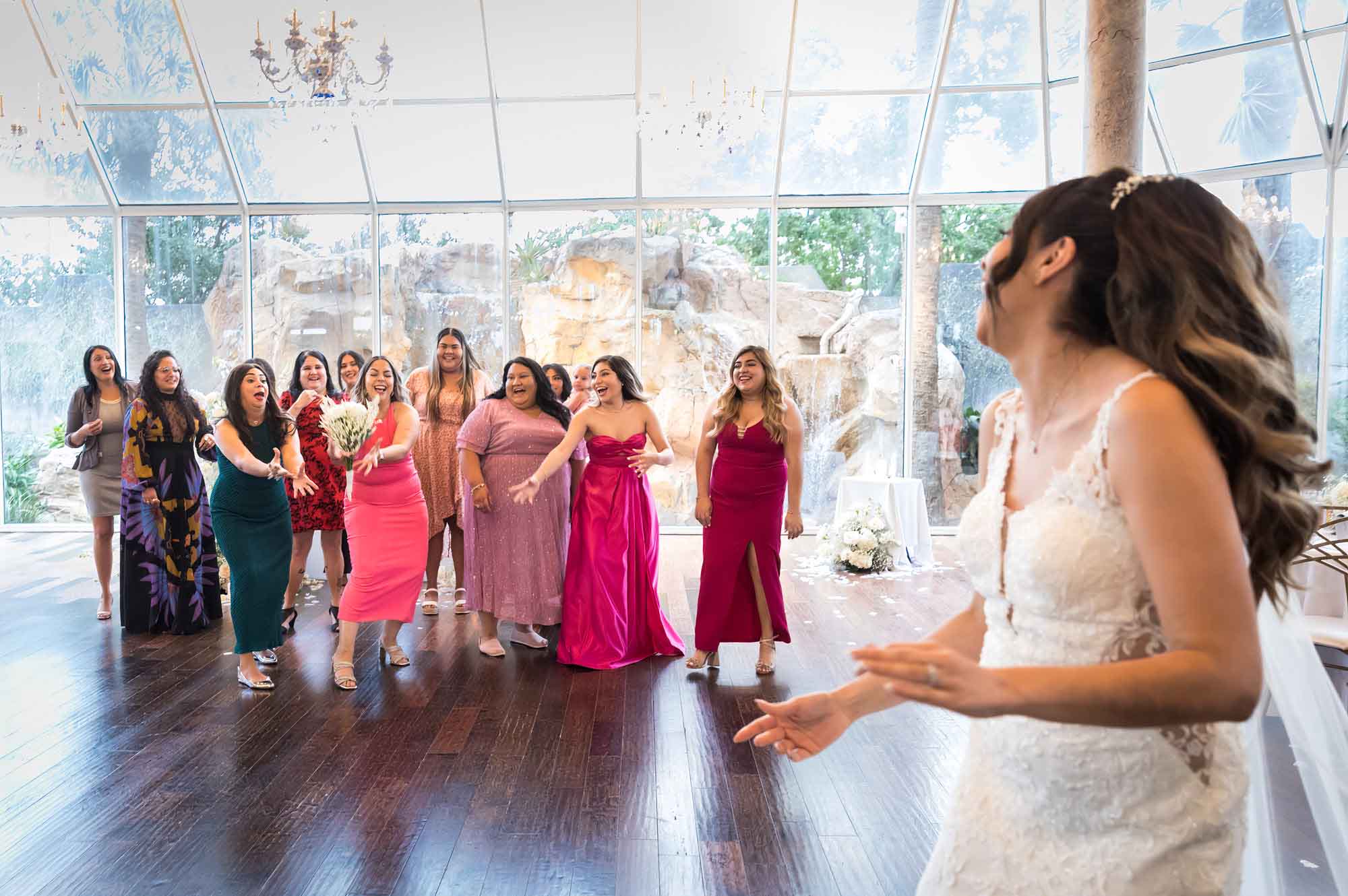Bride throwing bouquet to group of women at wedding reception for an article on affordable wedding venues in San Antonio
