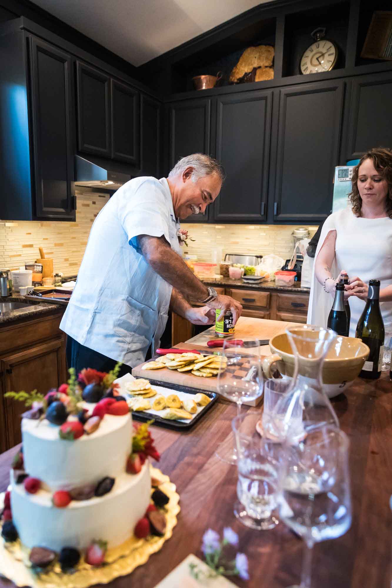Man cooking food in a kitchen as bride watches for an article on affordable wedding venues in San Antonio