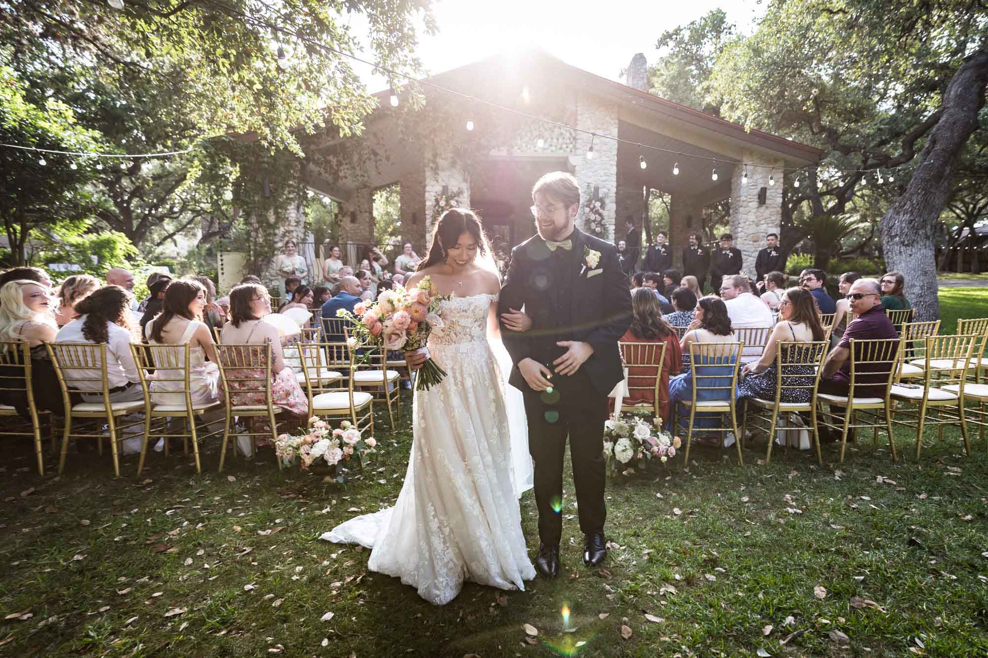 Bride and groom walking out of ceremony in sunlight at The Veranda for an article on affordable wedding venues in San Antonio