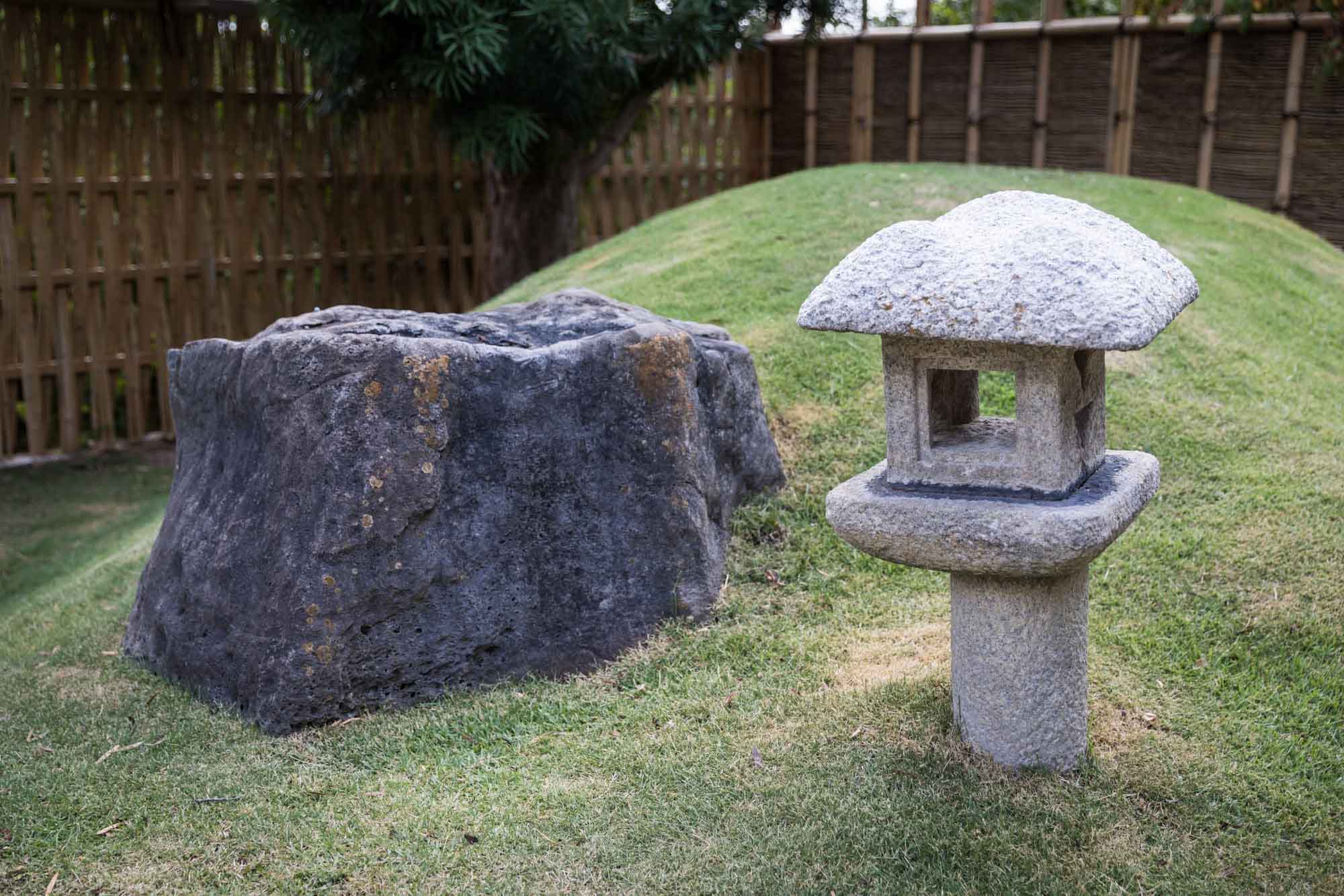 View of Kumamoto En Japanese Garden showing large grey stone and light grey stone lantern for an article on the best San Antonio Botanical Garden photo locations