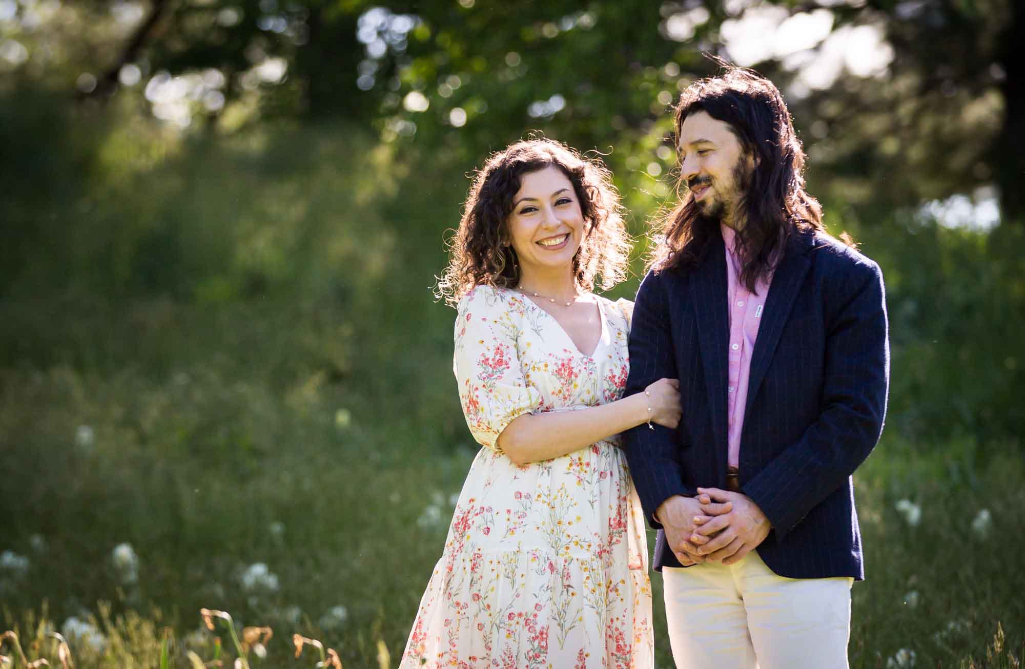 Woman hugging man's arm standing in front of green bushes and trees for an article on the best San Antonio Botanical Garden photo locations