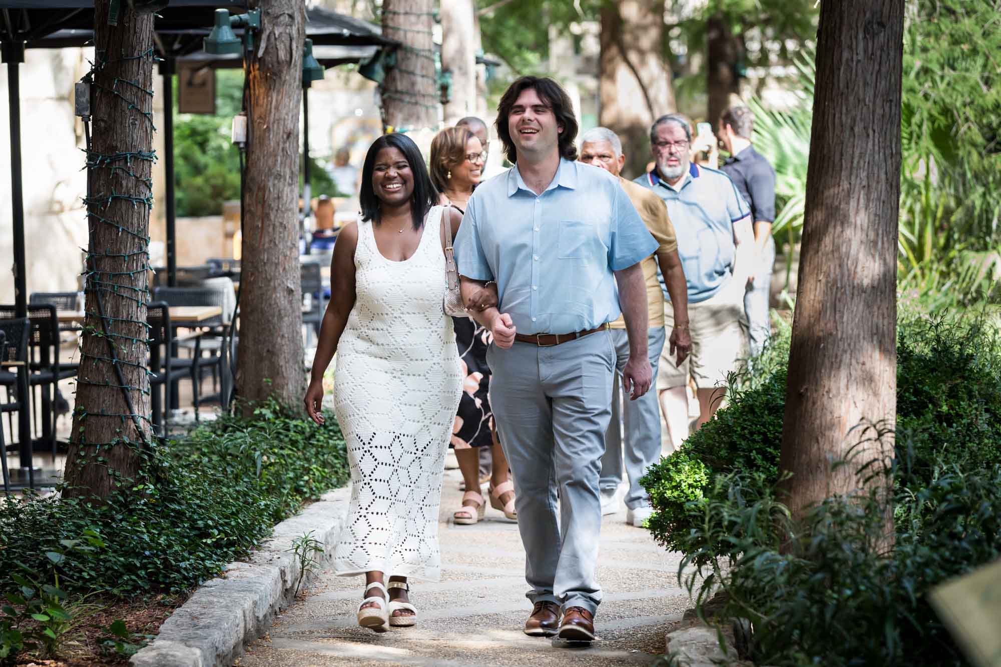 Couple walking in front of group of adults down River Walk pathway for an article on how to get married on a River Walk boat