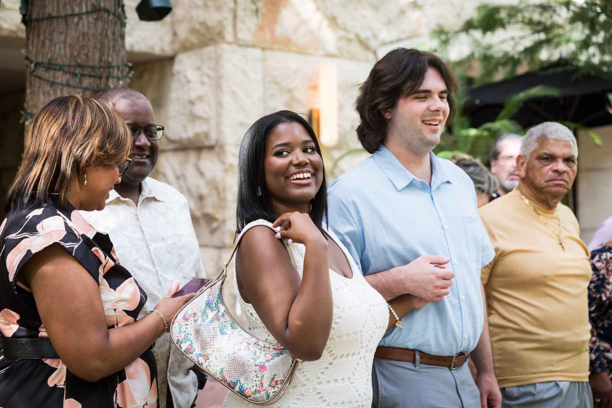 Group of adults standing in front of stone wall and tree for an article on how to get married on a River Walk boat