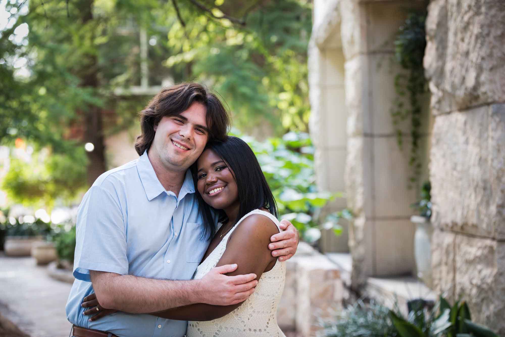 African American woman wearing white sleeveless dress hugging fiance wearing blue shirt for an article on how to get married on a River Walk boat