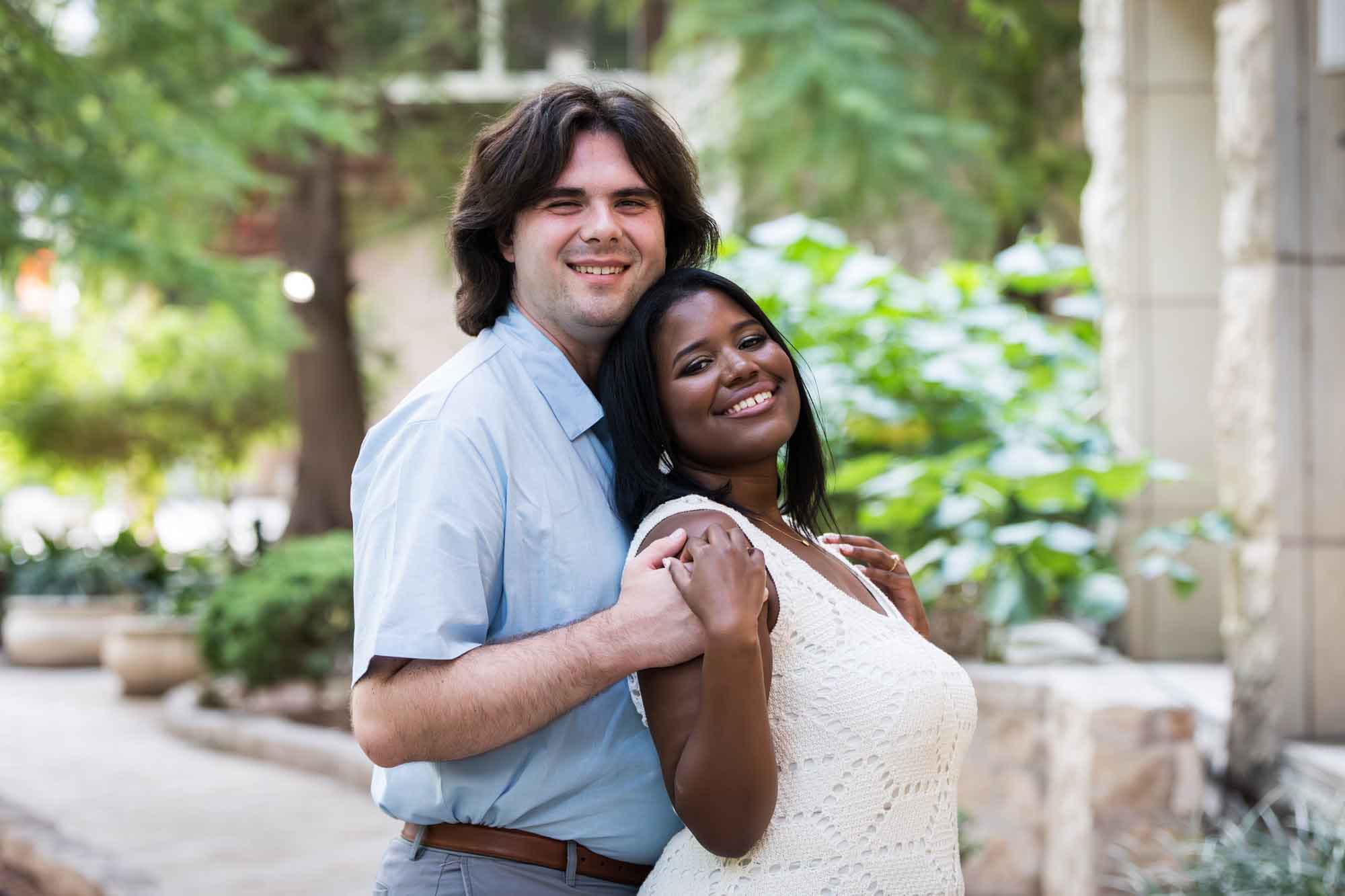 African American woman wearing white sleeveless dress hugging fiance wearing blue shirt for an article on how to get married on a River Walk boat