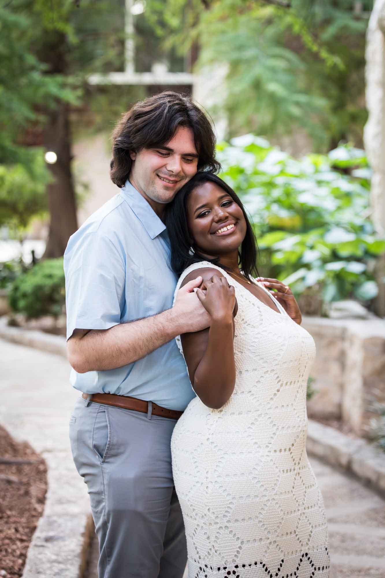African American woman wearing white sleeveless dress hugging fiance wearing blue shirt for an article on how to get married on a River Walk boat