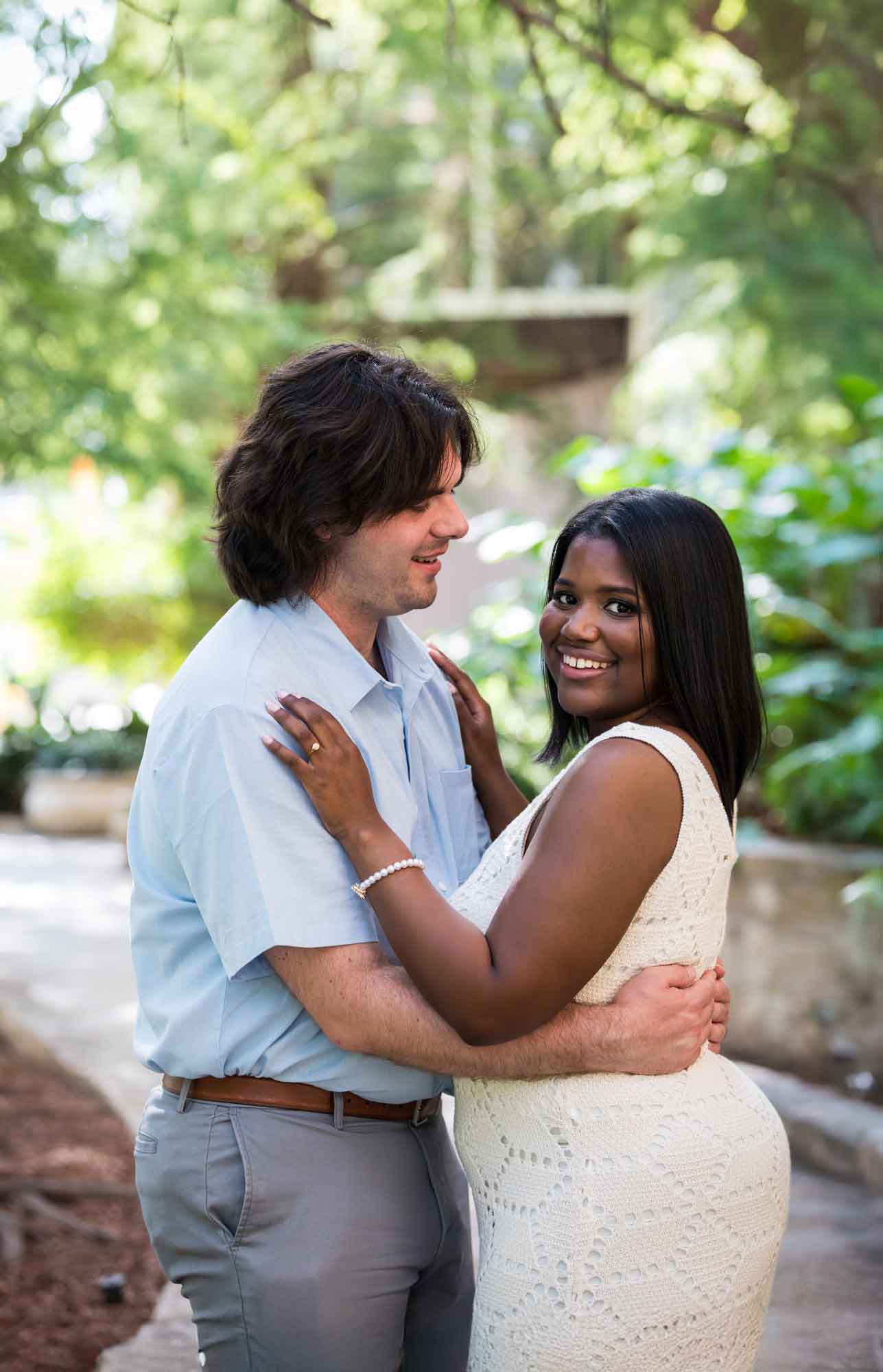 African American woman wearing white sleeveless dress hugging fiance wearing blue shirt for an article on how to get married on a River Walk boat