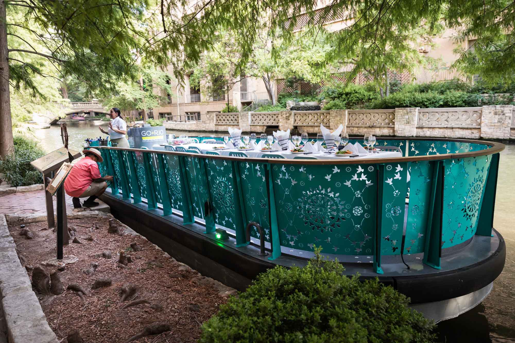 River Walk boat with blue decoration on sides being tied to dock by boat captain for an article on how to get married on a River Walk boat
