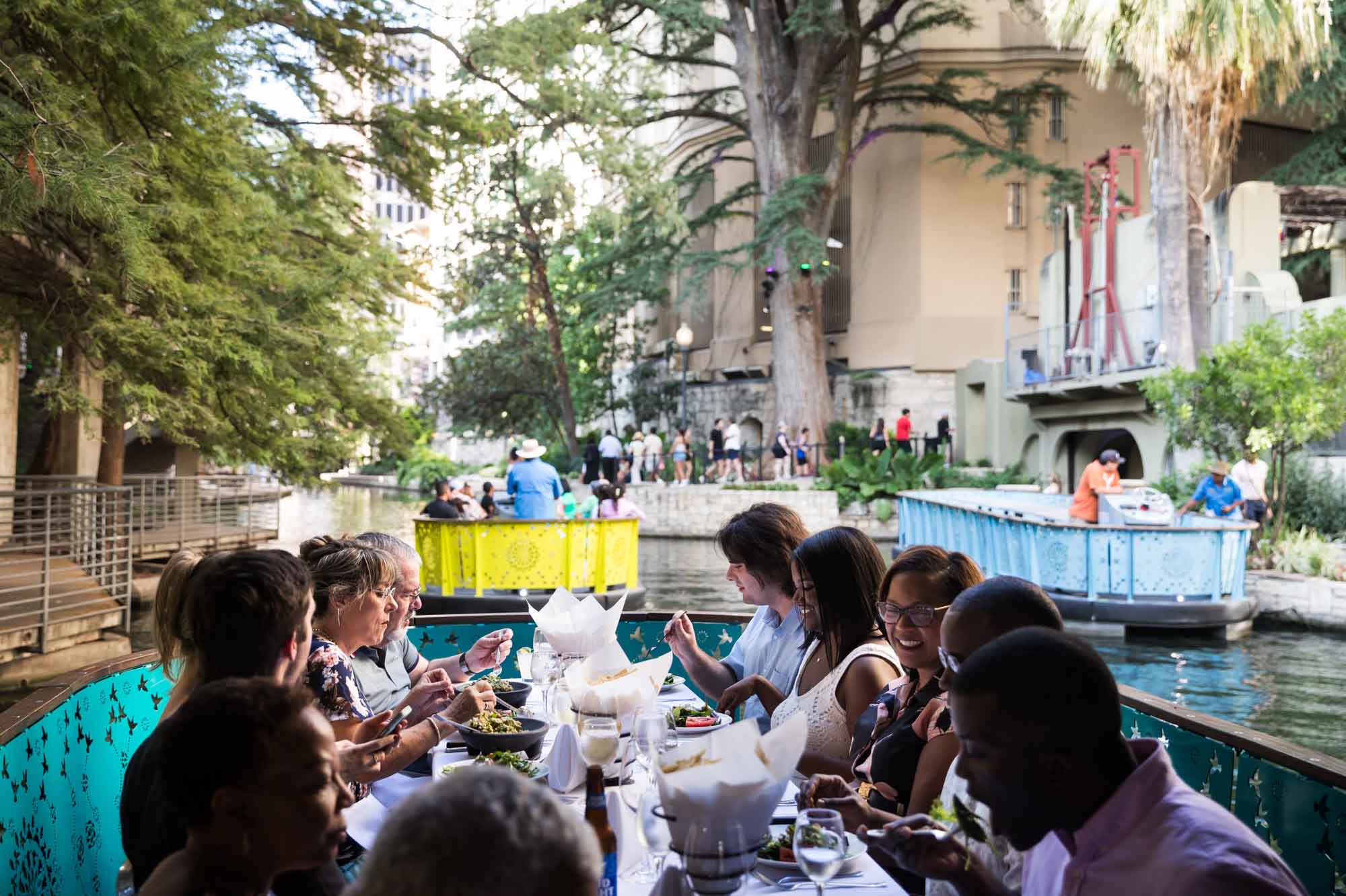 Group of guests eating on boat behind two other River Walk boats for an article on how to get married on a River Walk boat