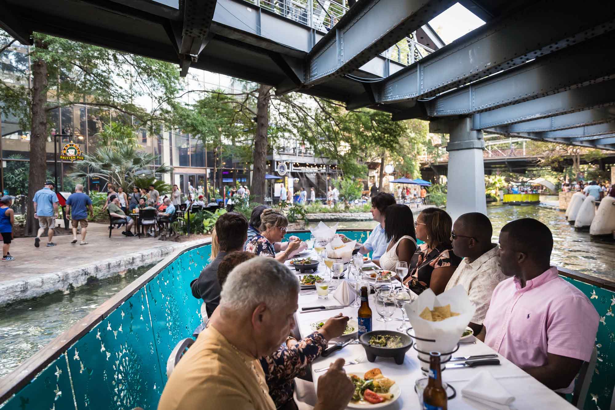 Group of guests seated at white table floating on boat down River Walk for an article on how to get married on a River Walk boat