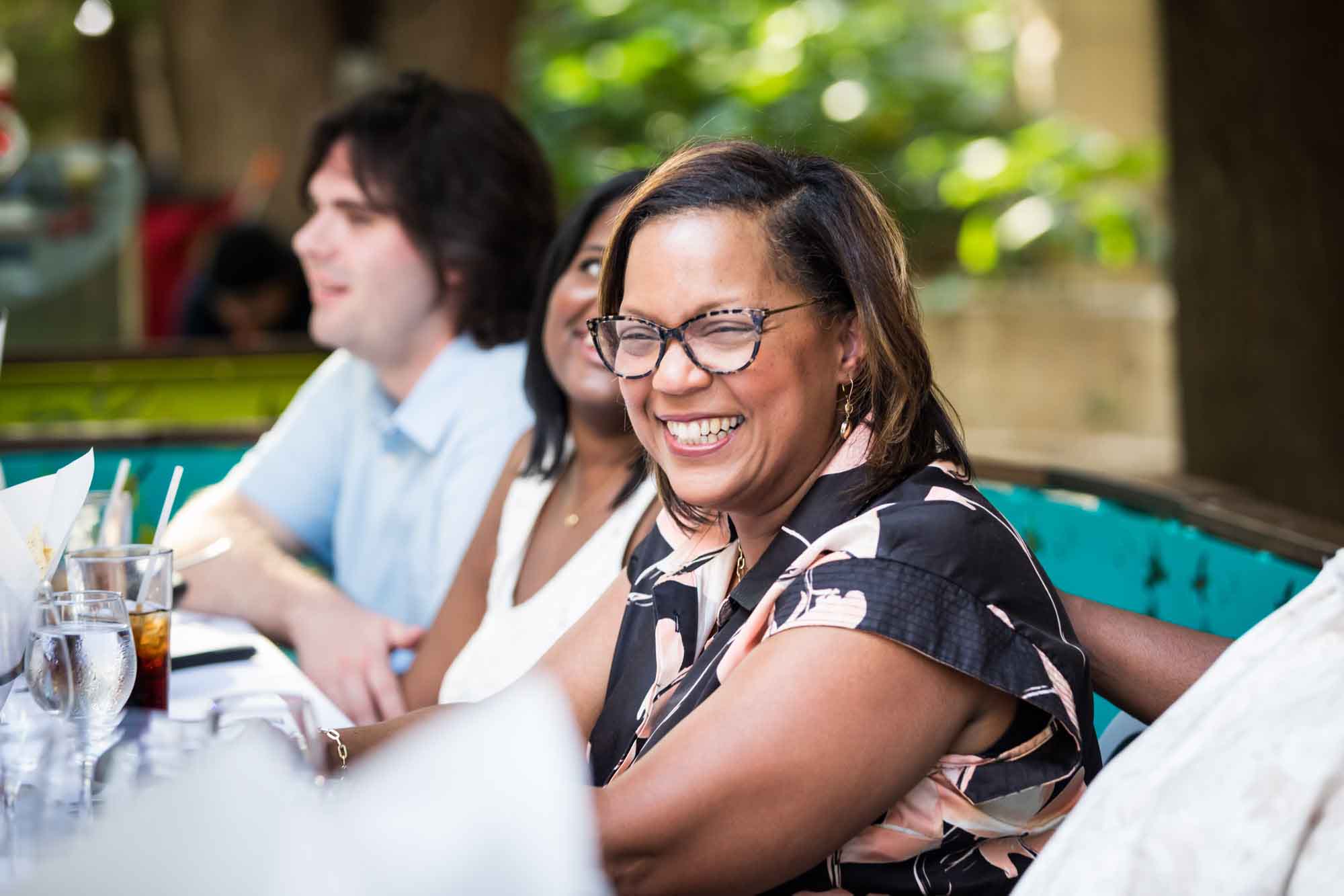 African American woman wearing glasses smiling wearing black floral dress for an article on how to get married on a River Walk boat