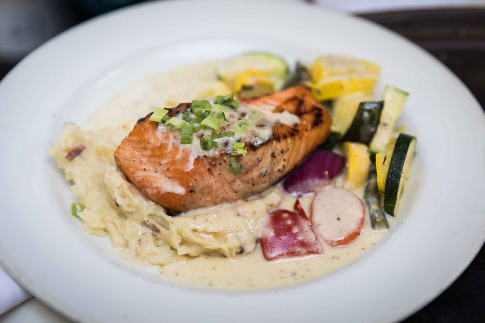 White plate set with dinner of salmon and vegetables for an article on how to get married on a River Walk boat