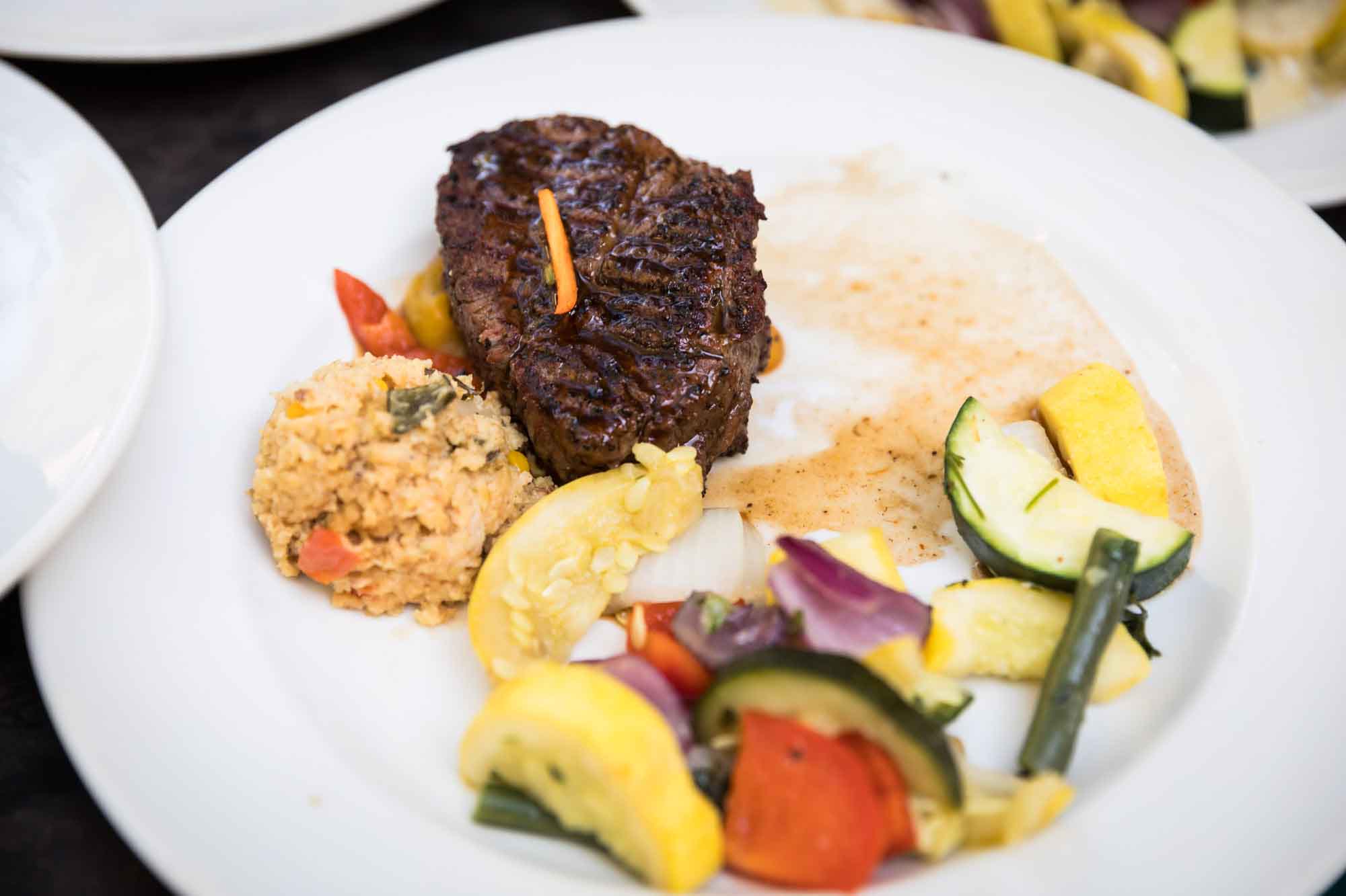 White plate set dinner of steak and vegetables for an article on how to get married on a River Walk boat