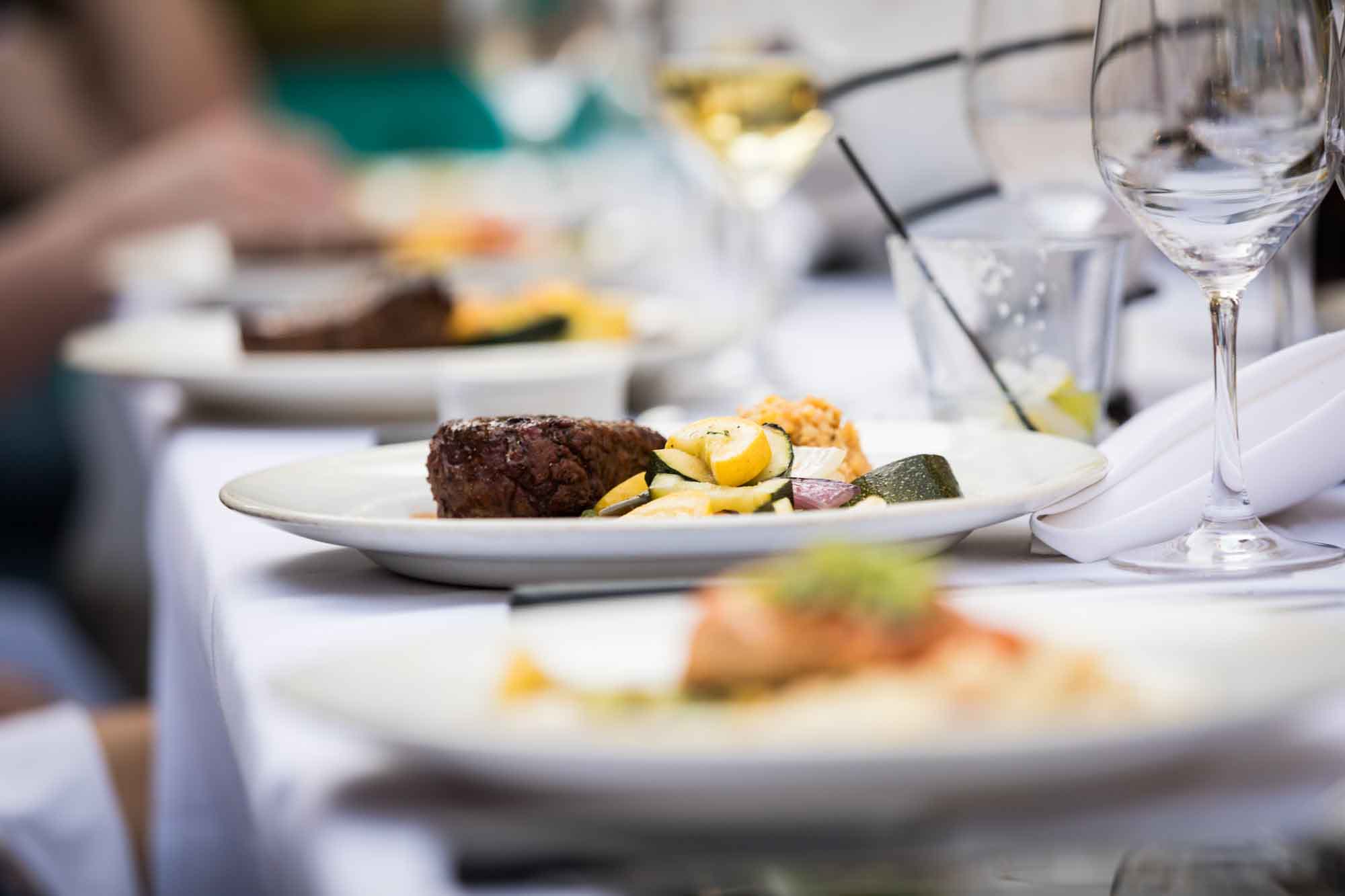 Close up on table set with plates of food and glasses during a dinner cruise for an article on how to get married on a River Walk boat
