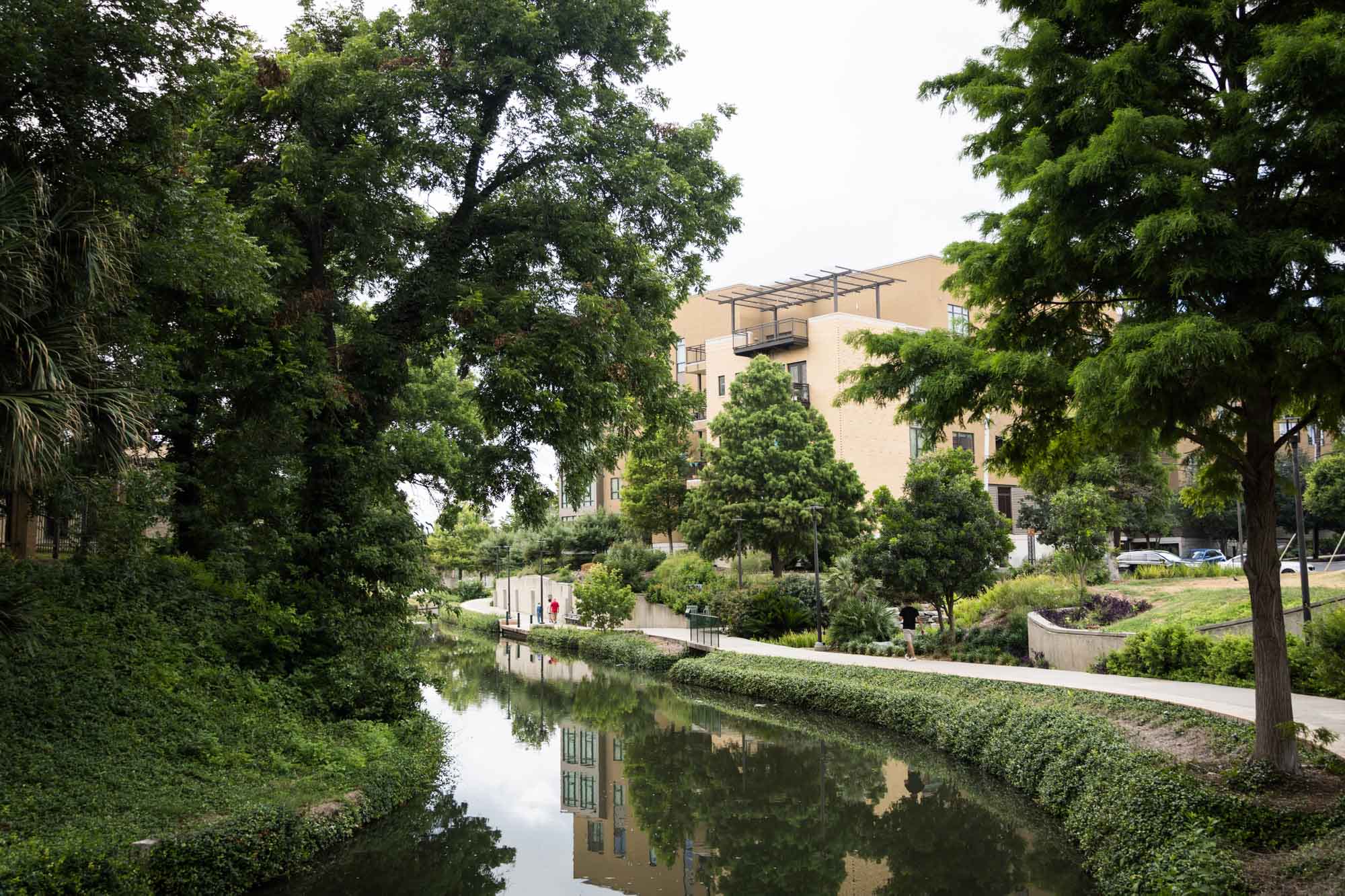 Scene along the River Walk in San Antonio, Texas with beige building and trees