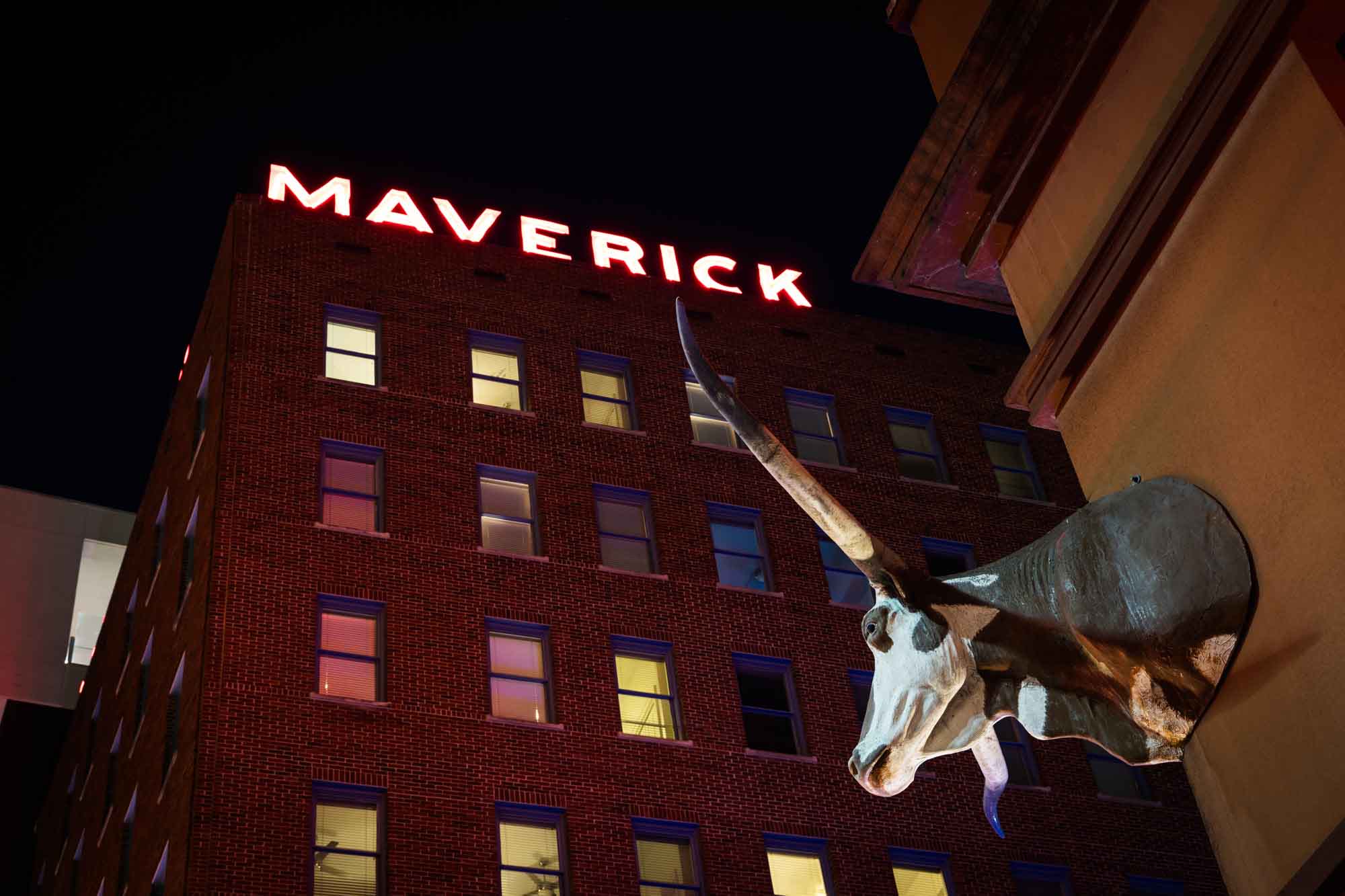 Longhorn steer head on Buckhorn Saloon front with neon sign of Maverick Building in the background