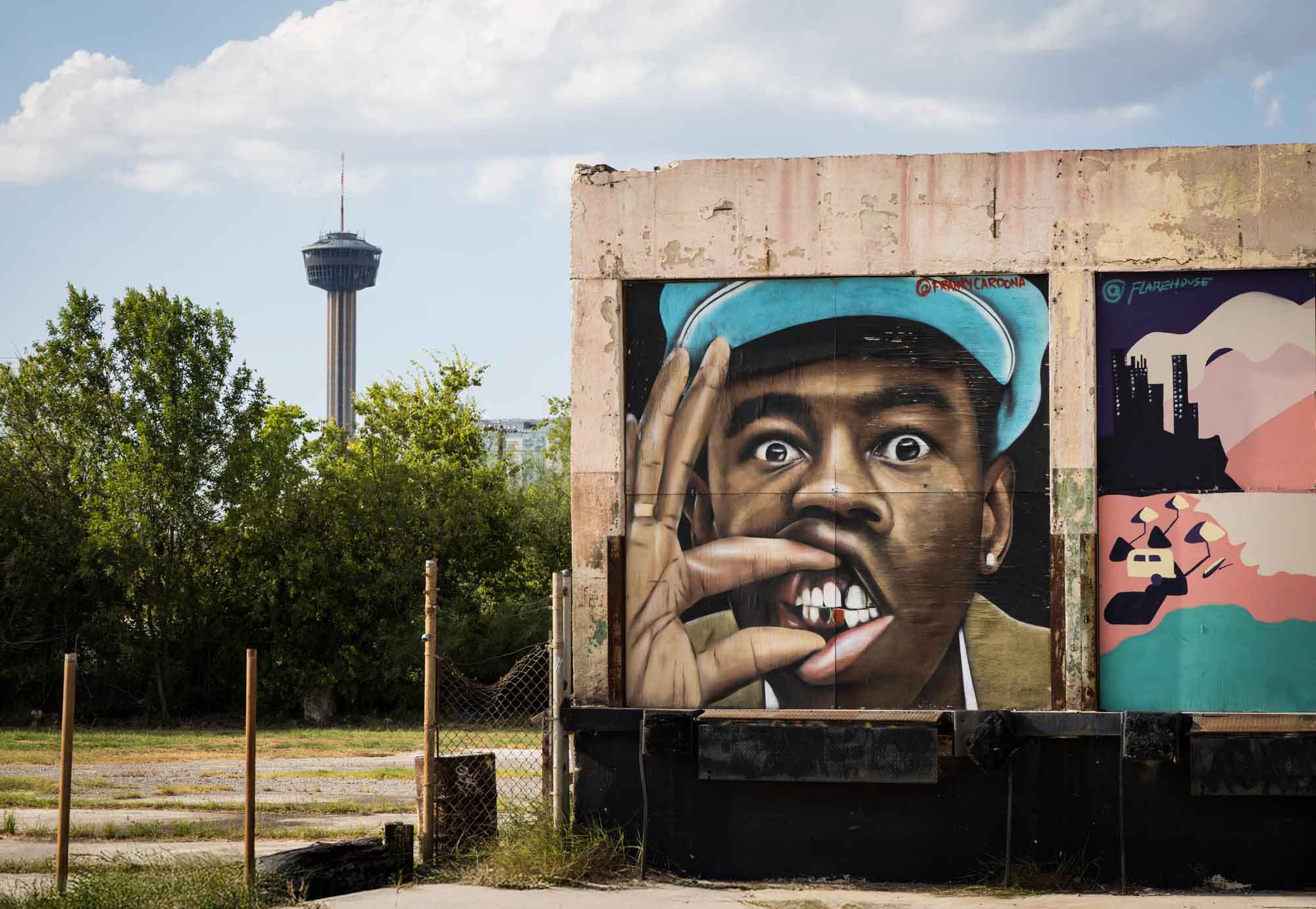 Mural of African American man showing teeth at Essex Modern City with Tower of the Americas in the background in San Antonio