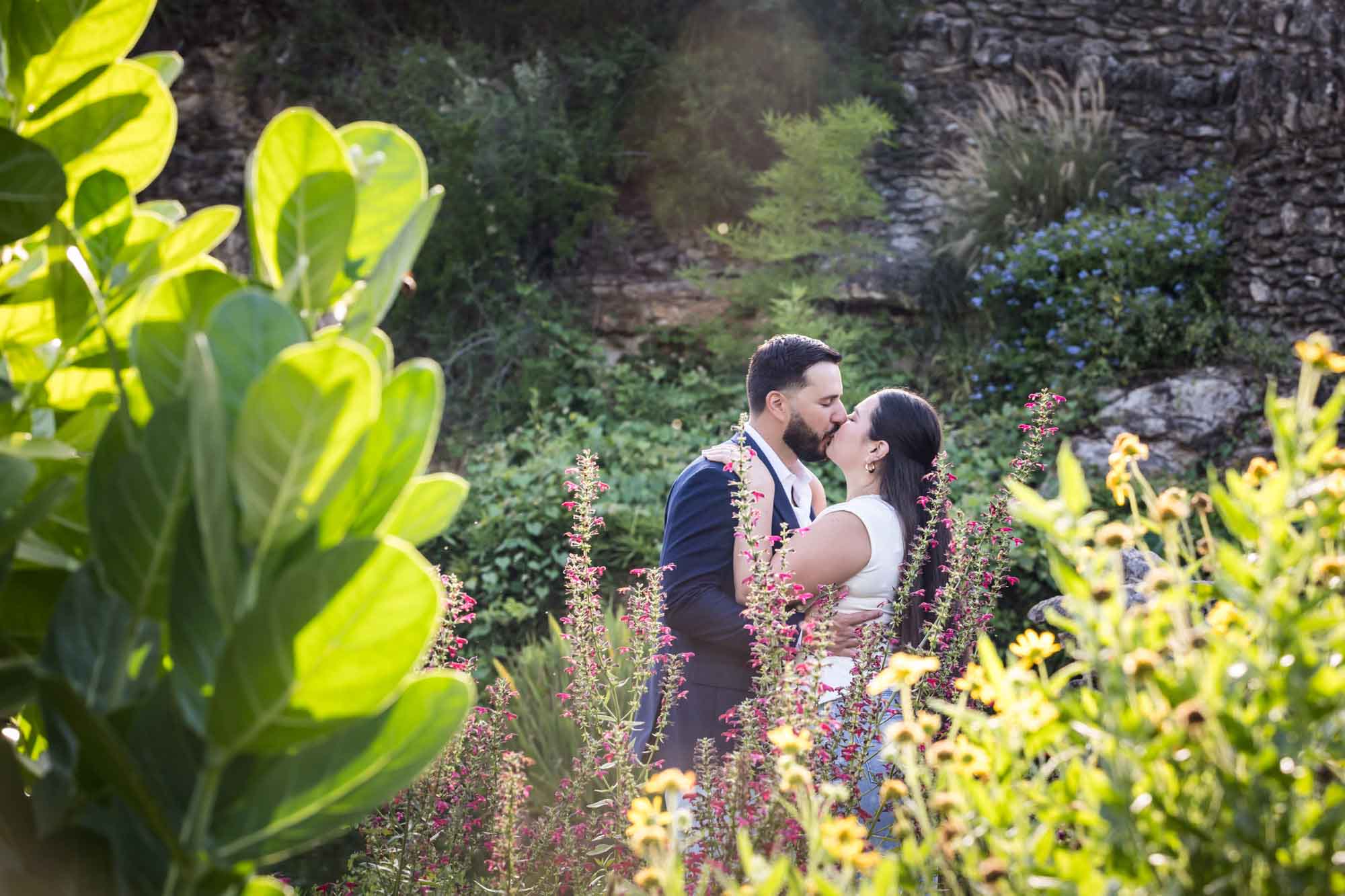 Couple kissing in middle of garden of colorful flowers for article on best Ziliker Botanical Garden photo locations