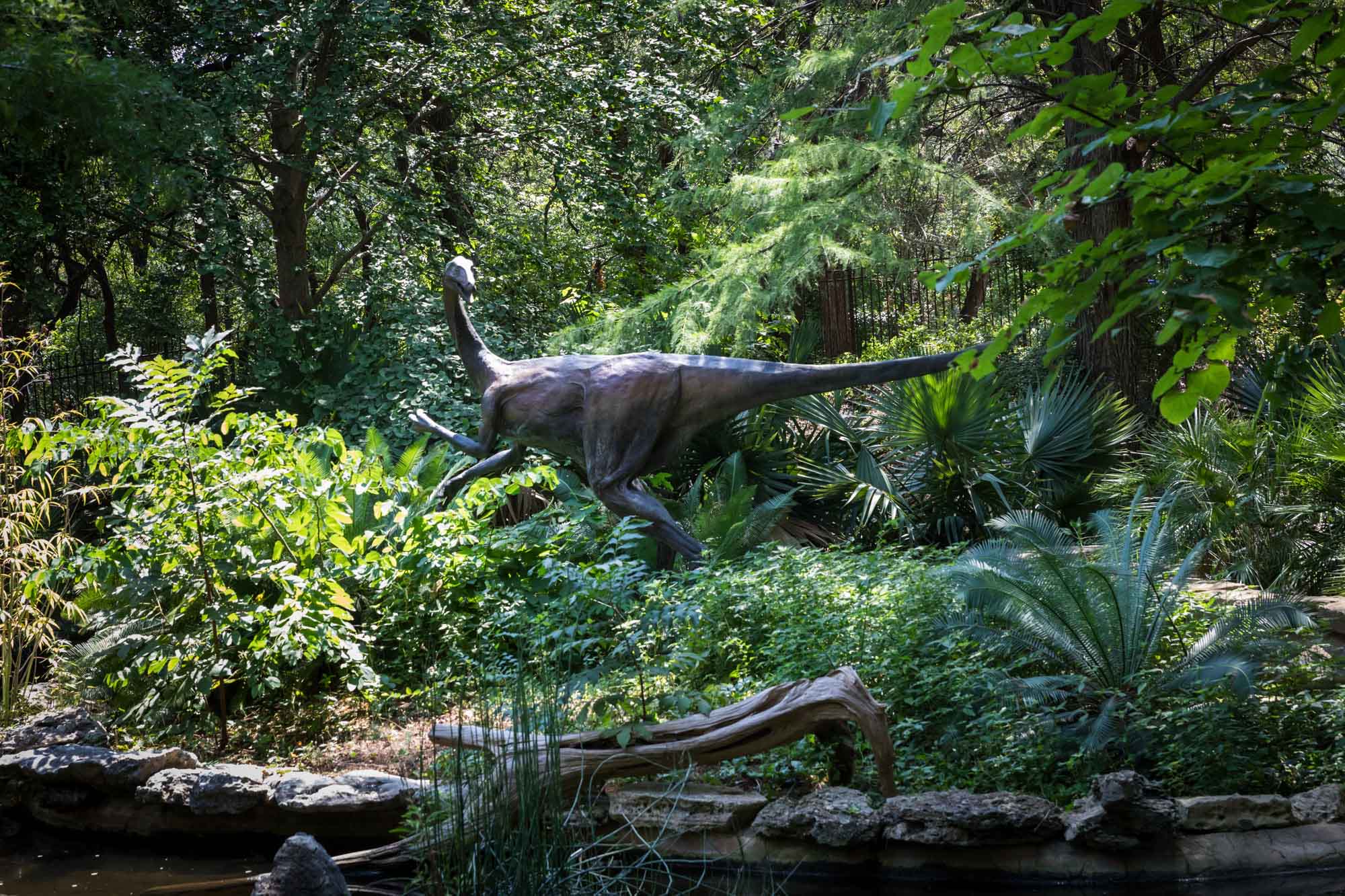 Large dinosaur sculpture surrounded by trees and plants in Hartman Prehistoric Garden for an article on the best Zilker Botanical Garden photo locations