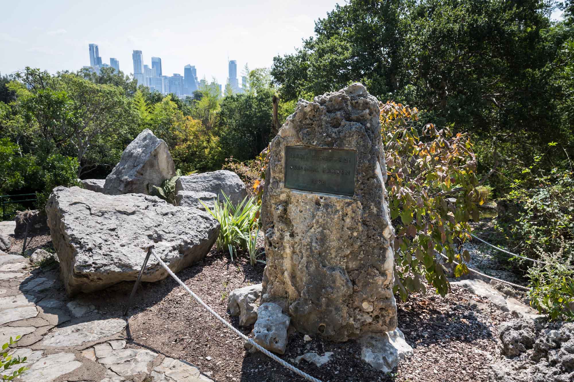 Natural stone plaque with view of downtown Austin in background for an article on the best Zilker Botanical Garden photo locations