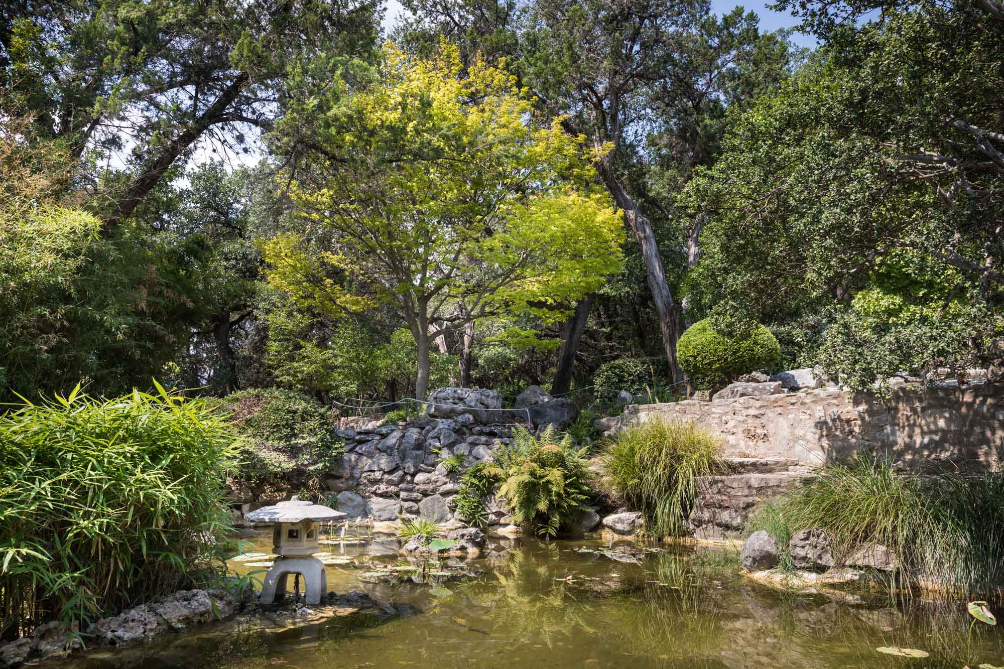 Pond and surrounding stone structures in Taniguchi Japanese Garden for an article on the best Zilker Botanical Garden photo locations