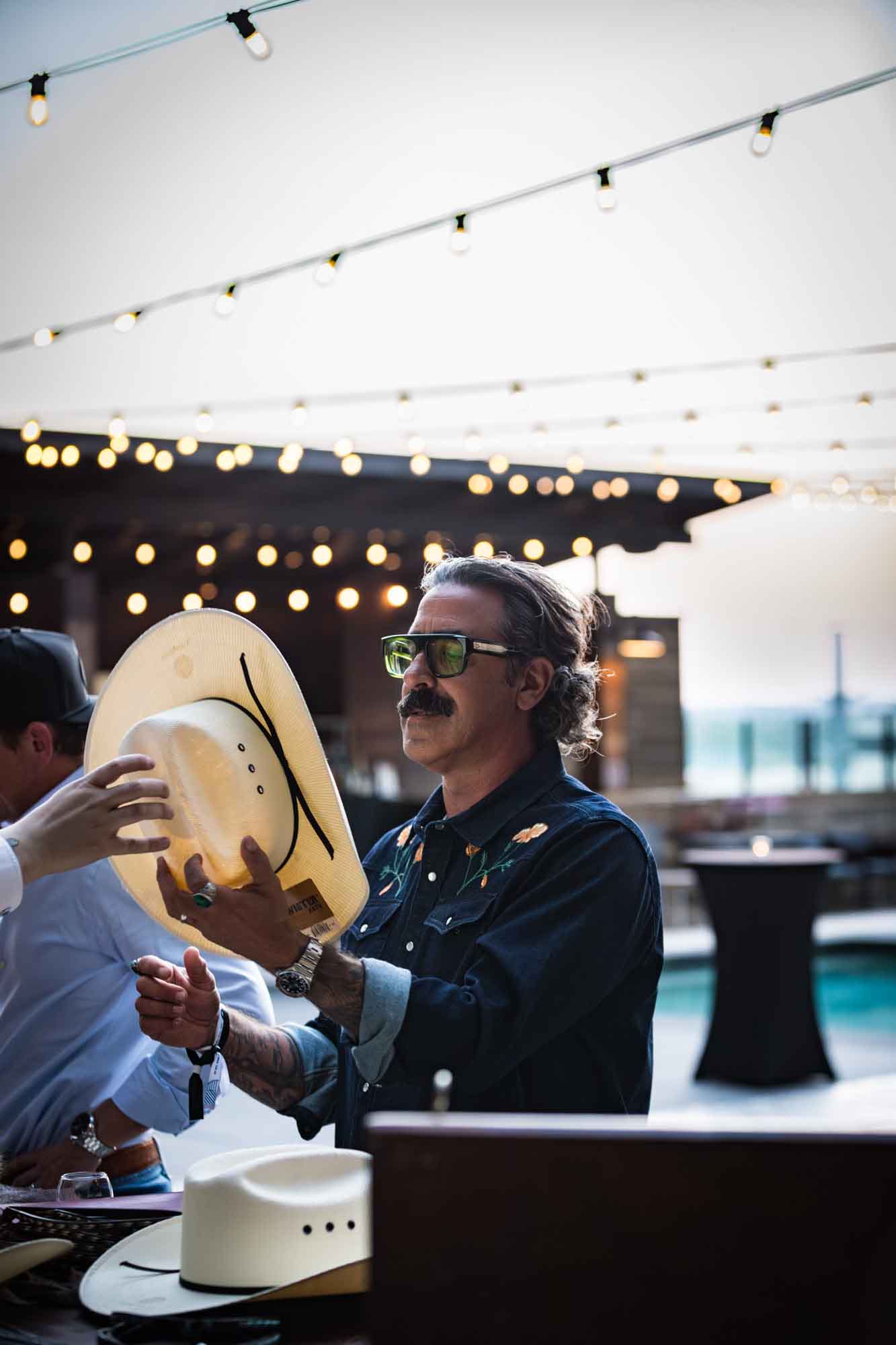Man wearing large classes accepting a white cowboy hat during a Hotel Van Zandt corporate event