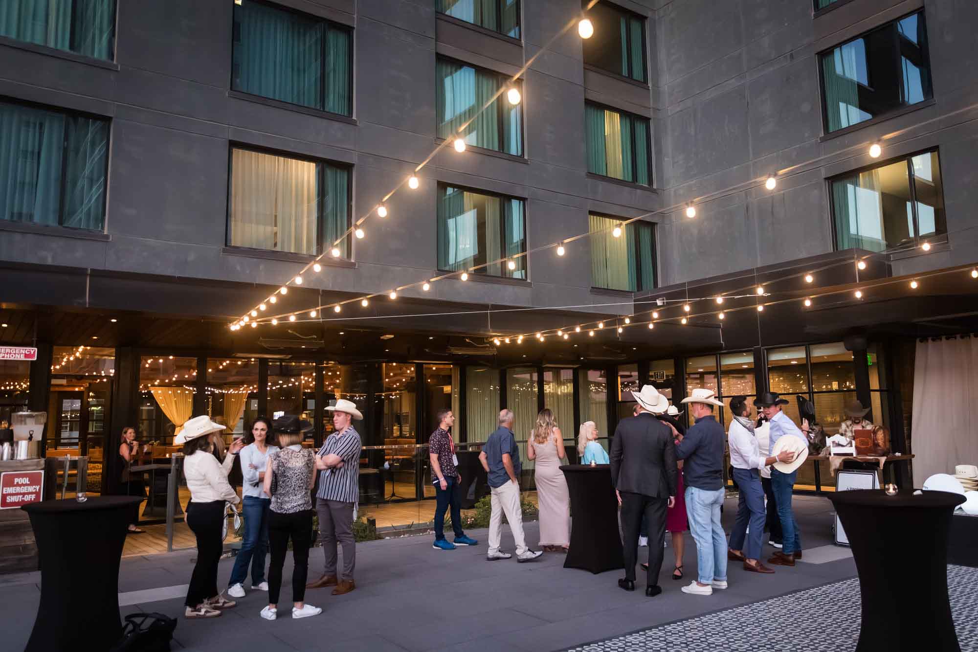 Guests mingling on the pool deck under string of lights at the Hotel Van Zandt during corporate event