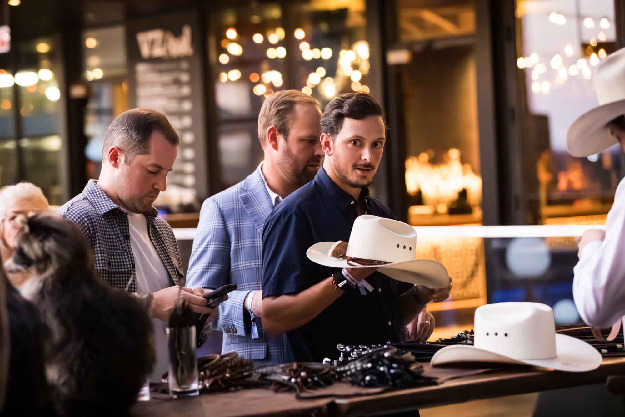 Guest holding white cowboy hat in front of two other male guests during a Hotel Van Zandt corporate event