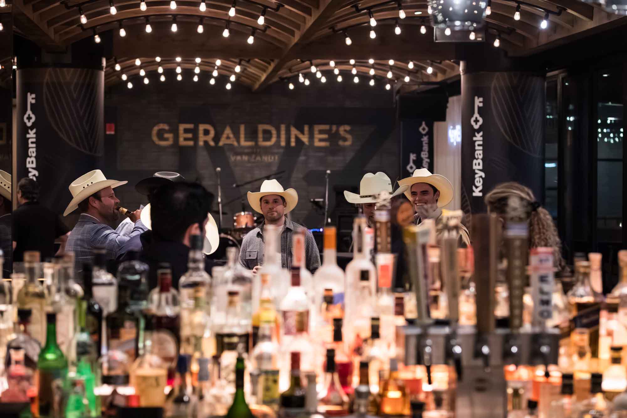 View over liquor bottles of guests wearing cowboy hats during a Hotel Van Zandt corporate event