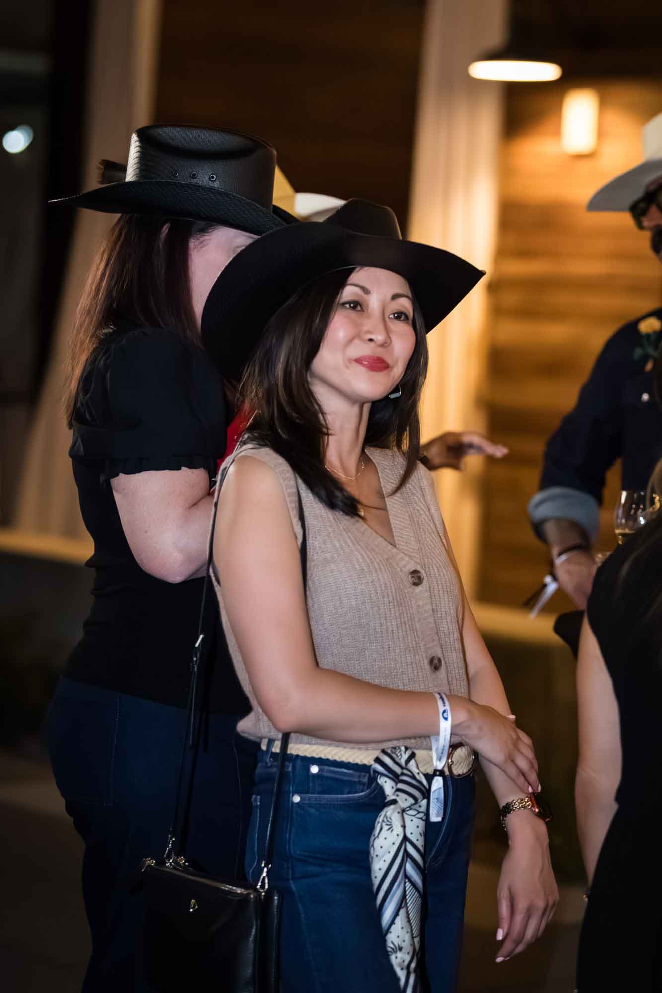 Asian woman wearing black cowboy hat and sleeveless beige sweater during a Hotel Van Zandt corporate event