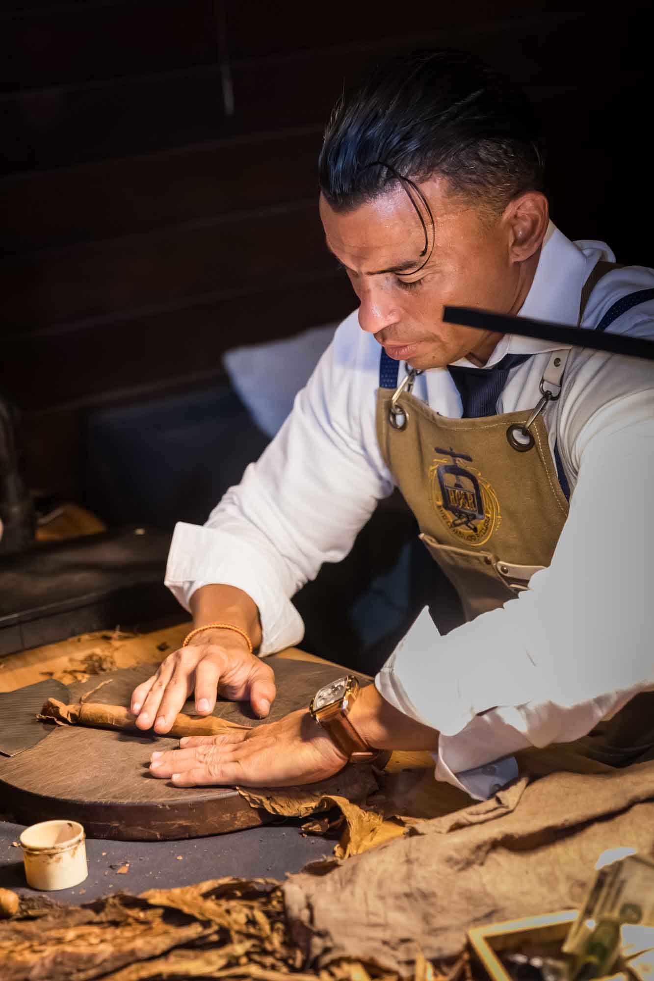 Ibrahim Ruiz rolling a cigar at a table during a Hotel Van Zandt corporate event