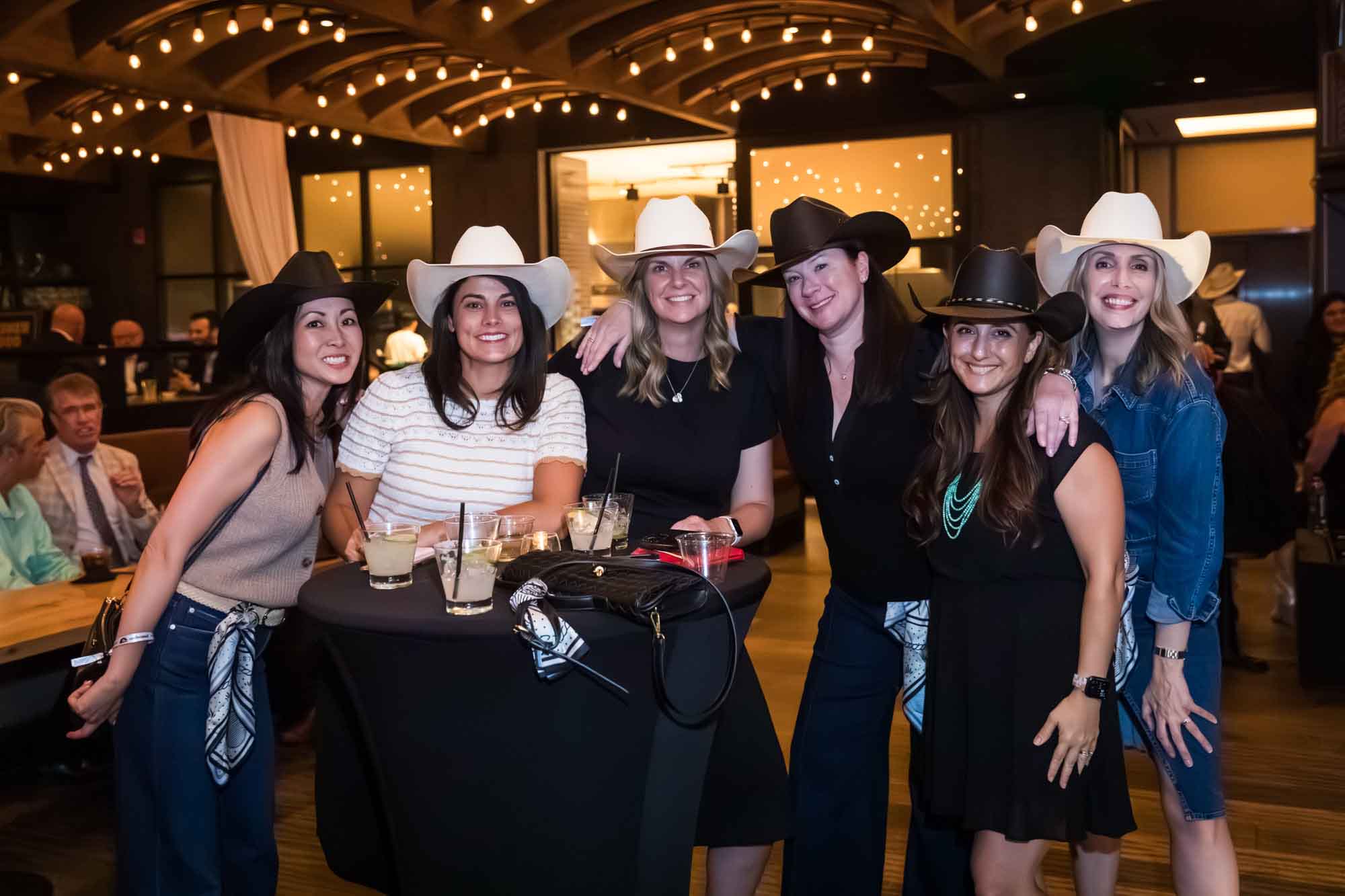 Group of six women wearing cowboy hats looking into camera during a Hotel Van Zandt corporate event