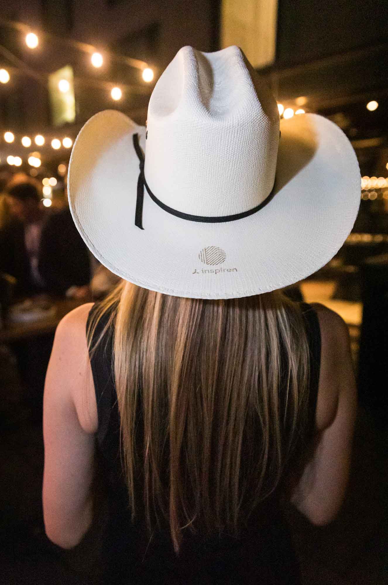 Woman with long blonde hair turned around wearing white cowboy hat during a Hotel Van Zandt corporate event