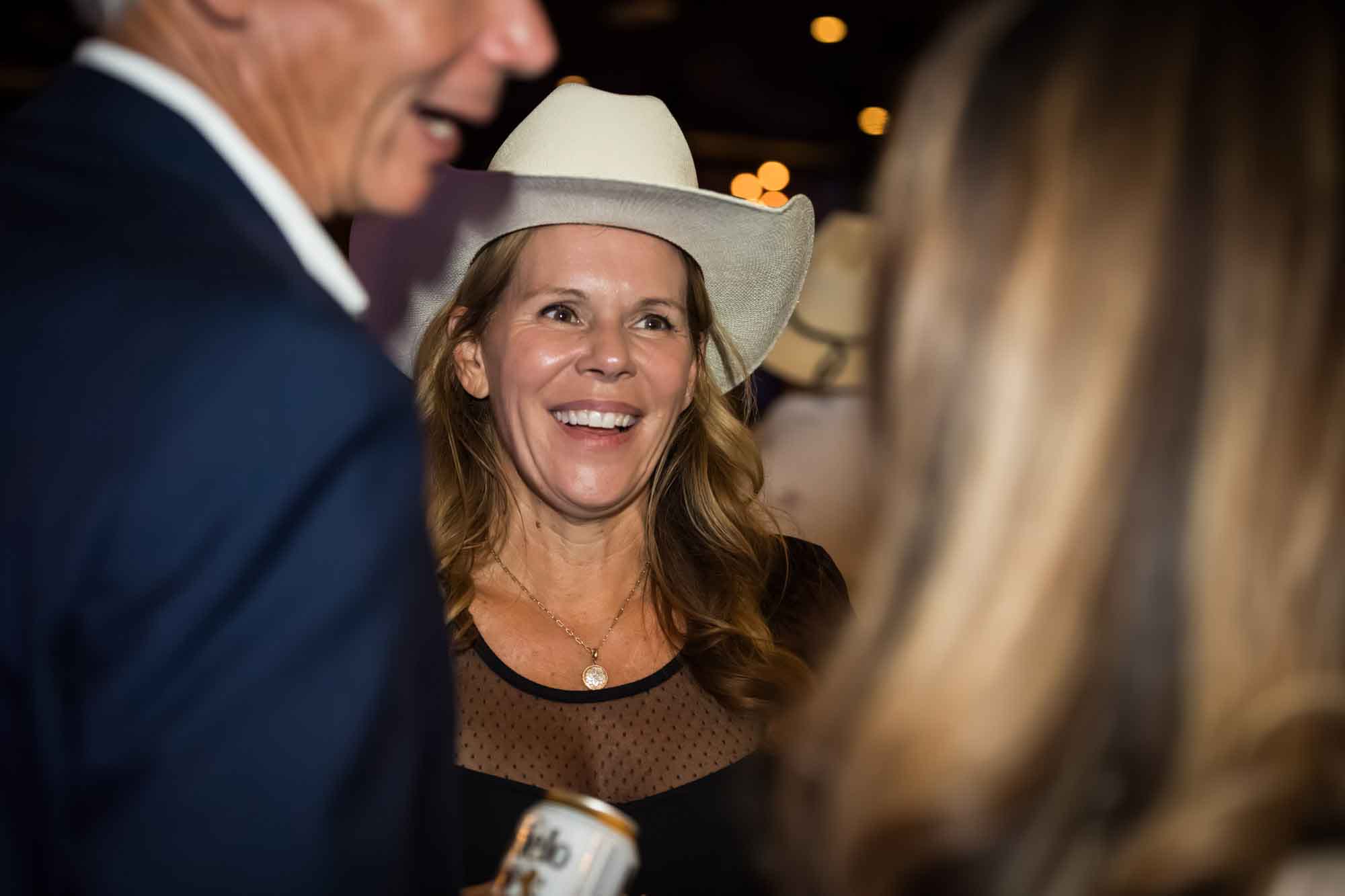 Blonde-haired woman wearing white cowboy hat in between people during a Hotel Van Zandt corporate event